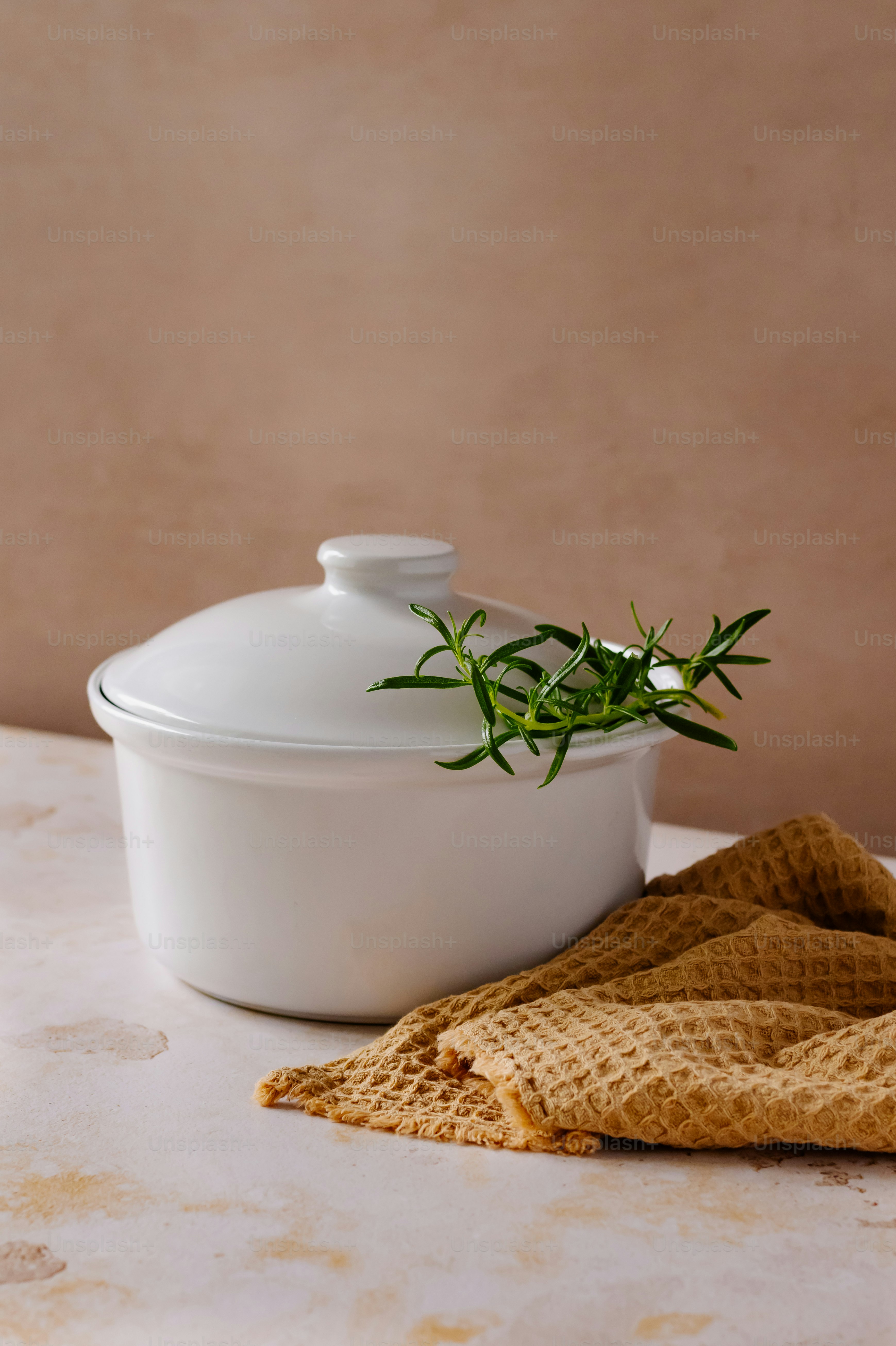 a white casserole dish with a sprig of rosemary