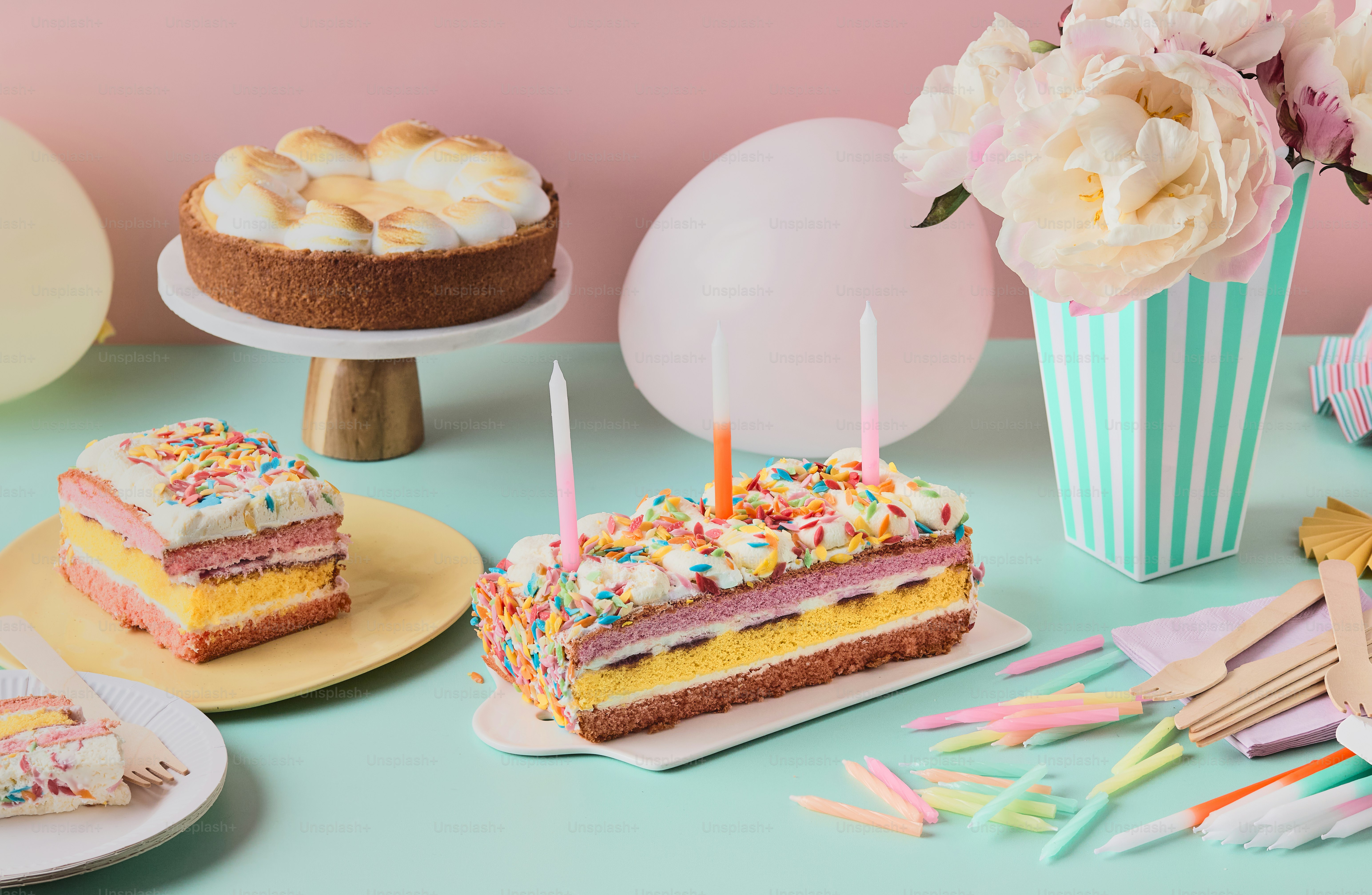 Birthday cakes on surface with flowers and party decorations.