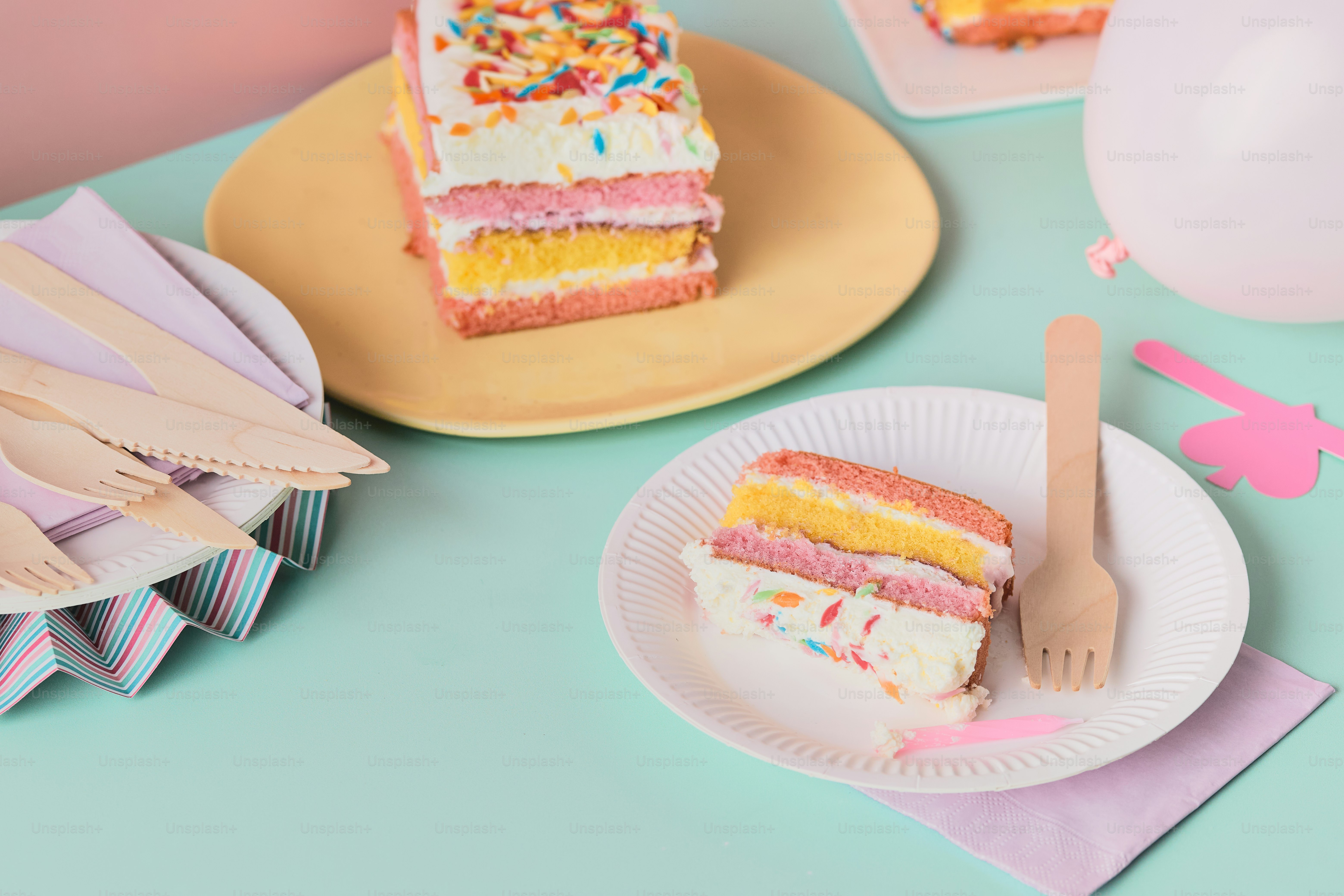 Sliced rainbow cake on plates.