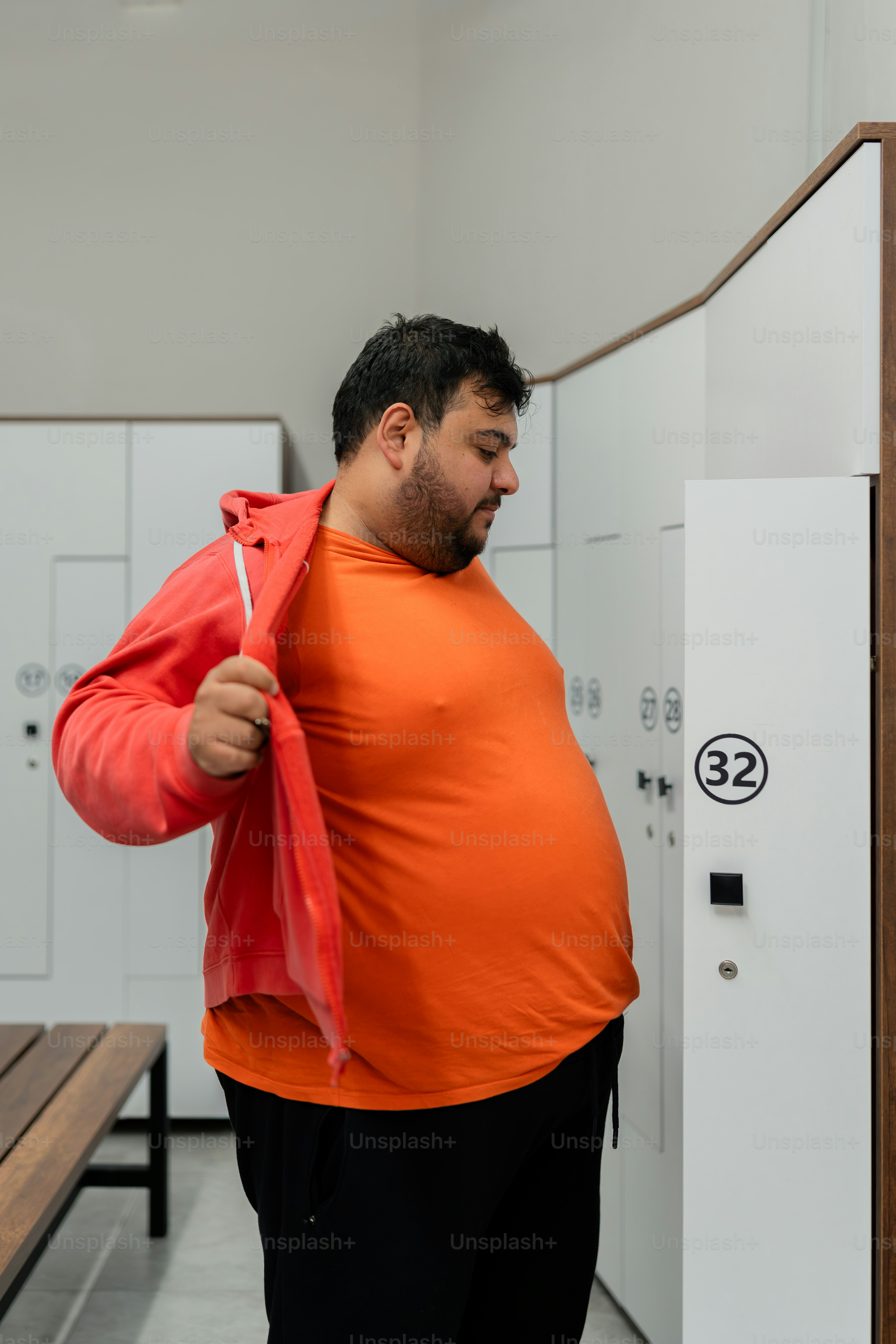 a man in an orange shirt is holding a red jacket