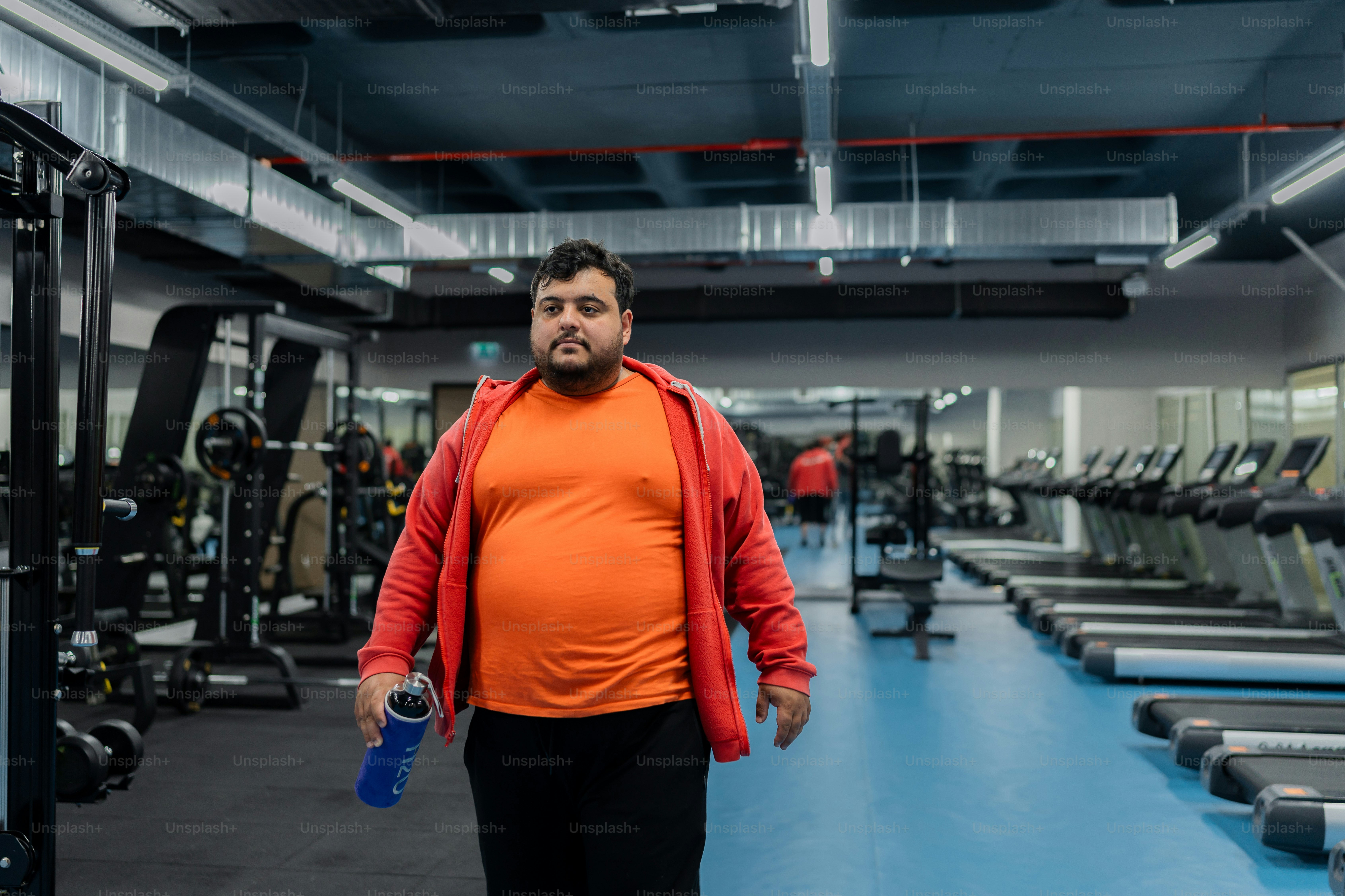 a man standing in a gym holding a water bottle