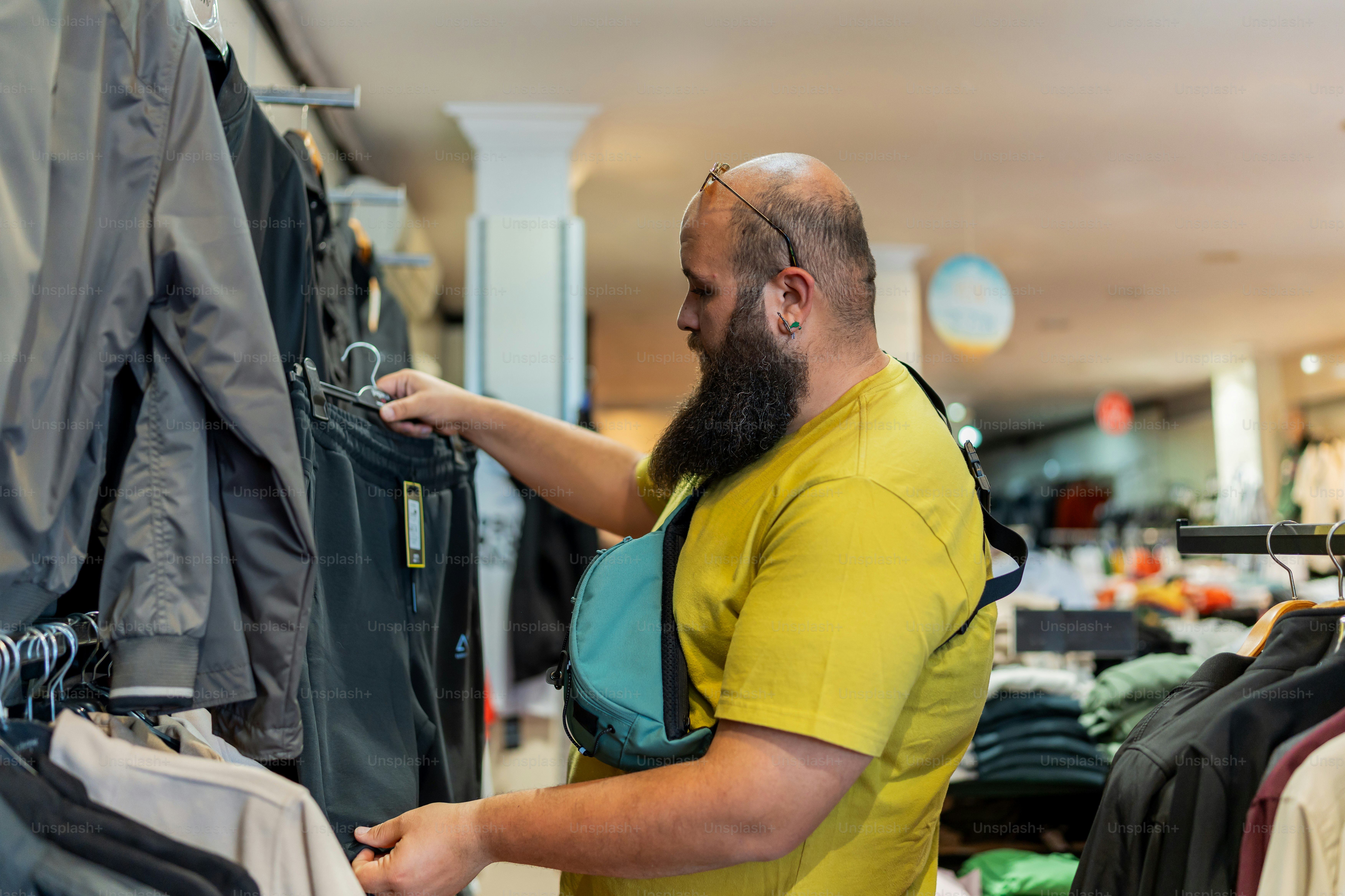 a man in a yellow shirt is looking at clothes