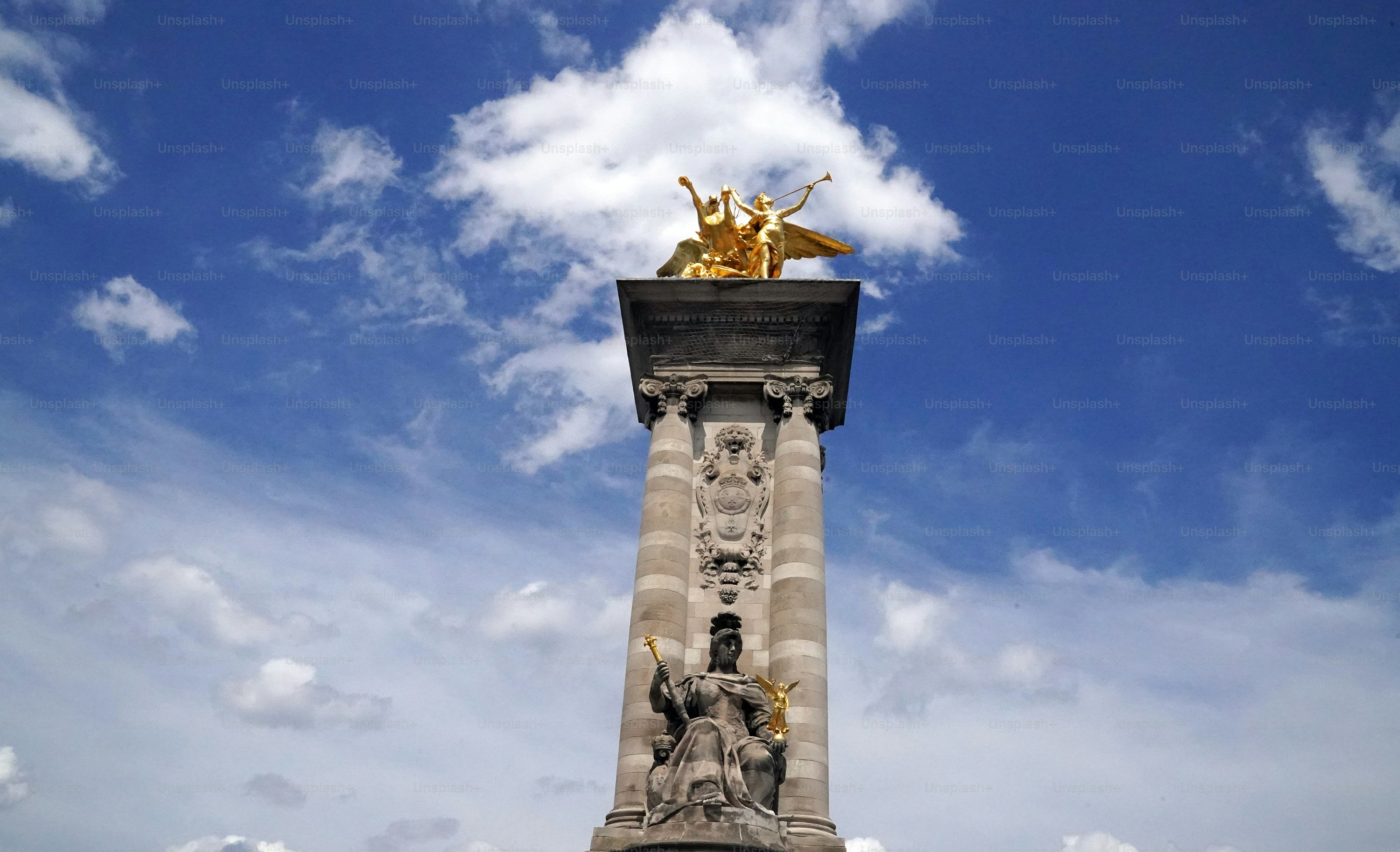 una statua in cima a un pilastro con uno sfondo di cielo