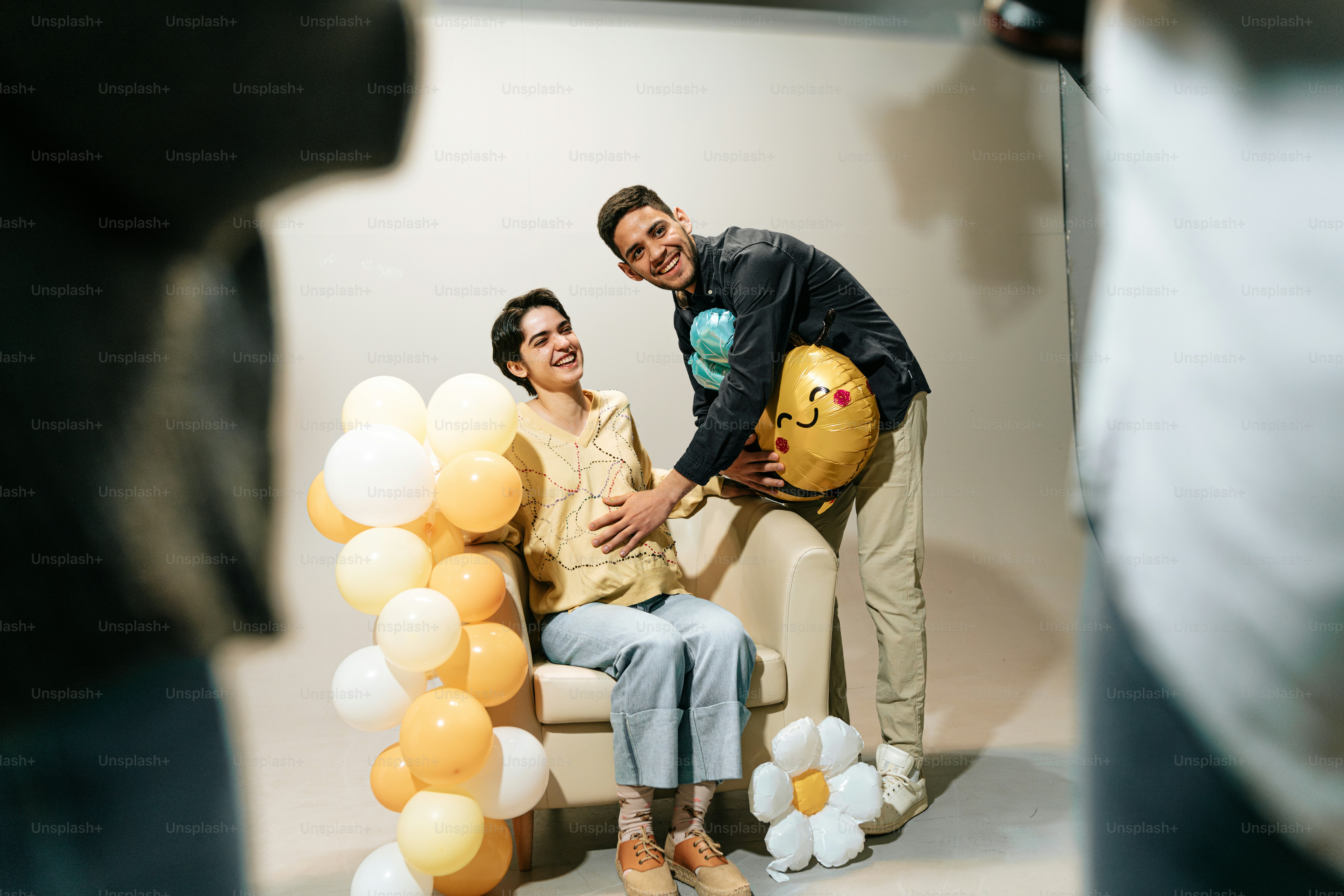 a man and woman sitting on a chair with balloons