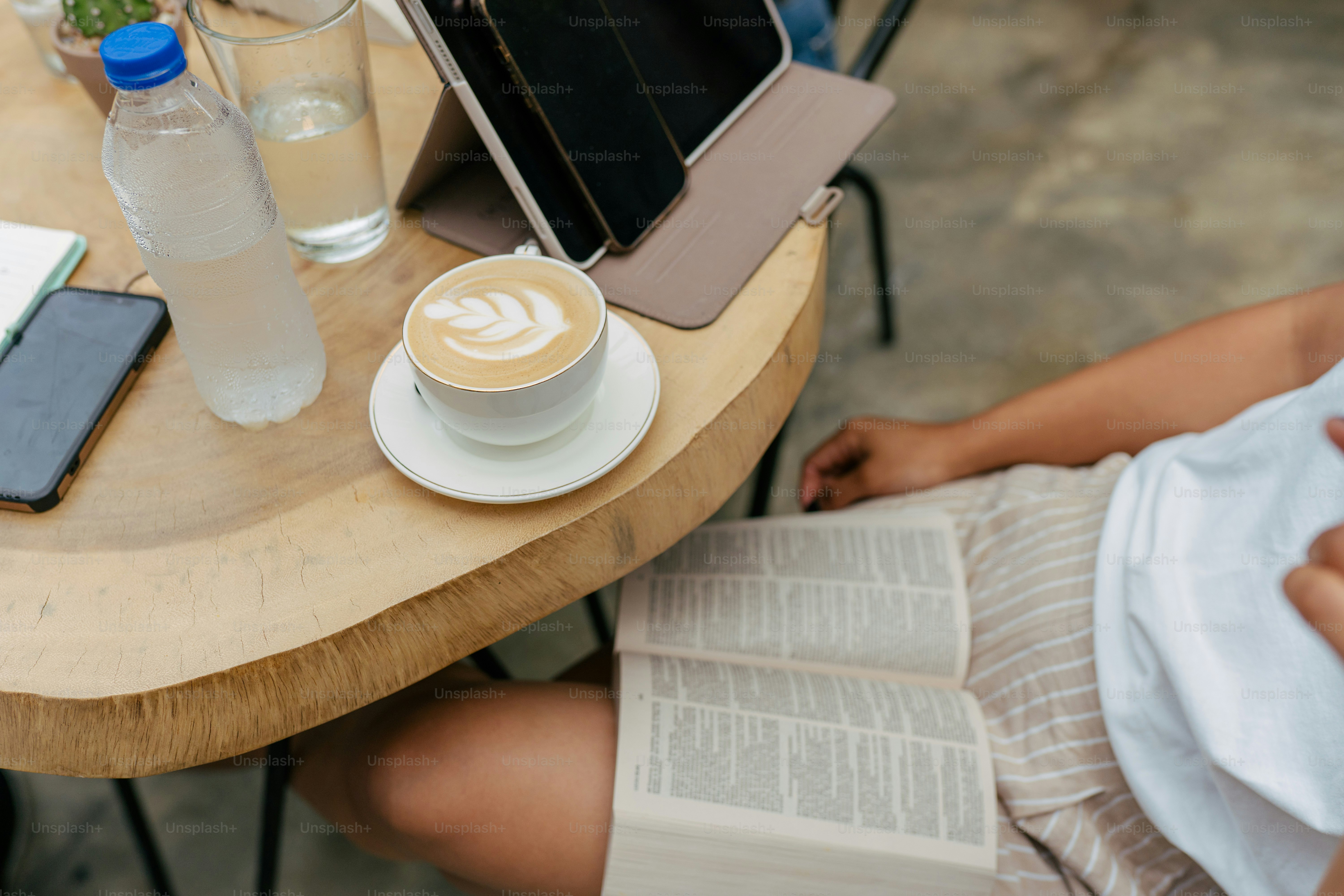 a person sitting at a table with a book and a cup of coffee