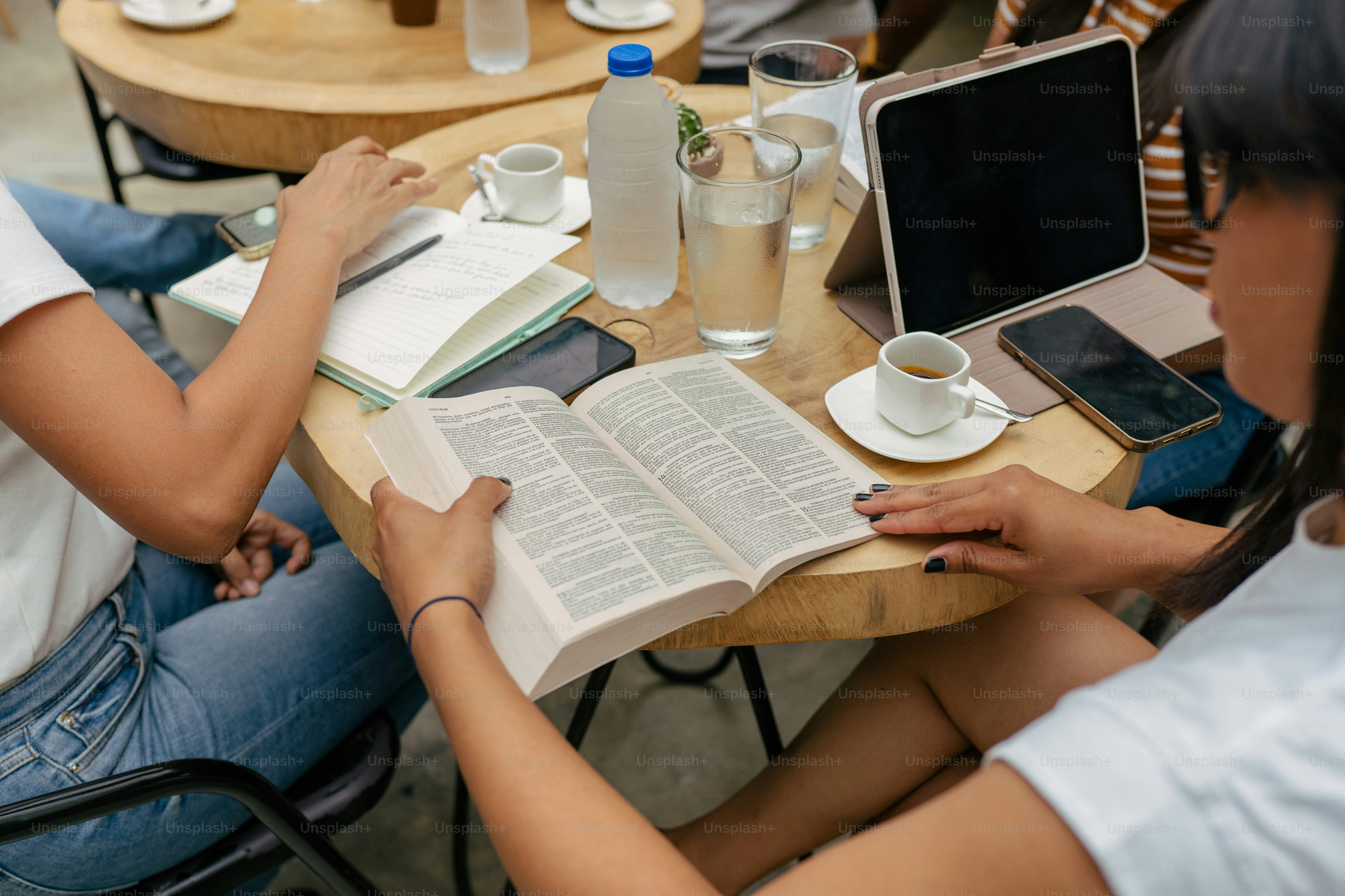 two people sitting at a table with open books