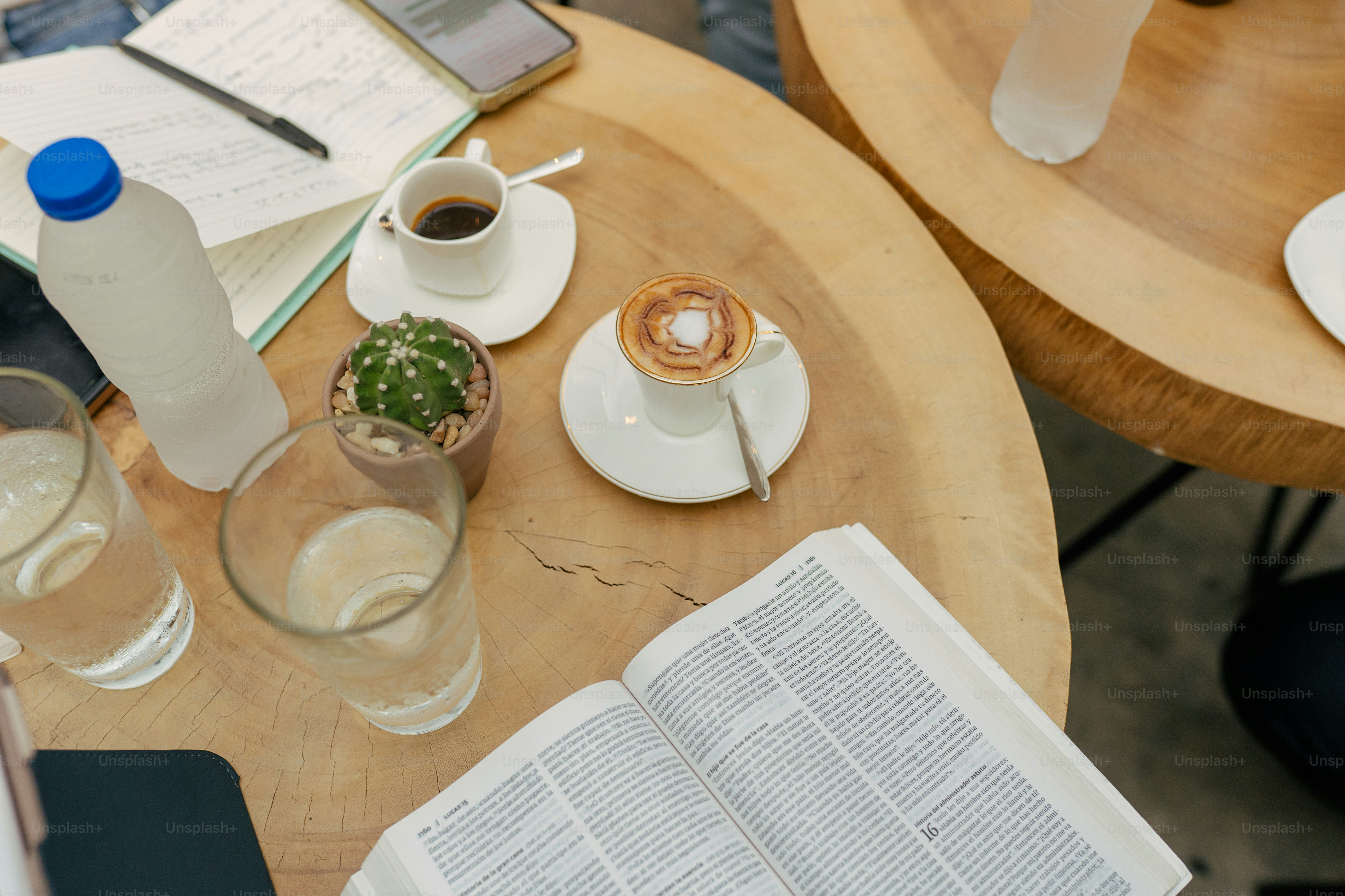 a wooden table topped with two glasses of water and a book