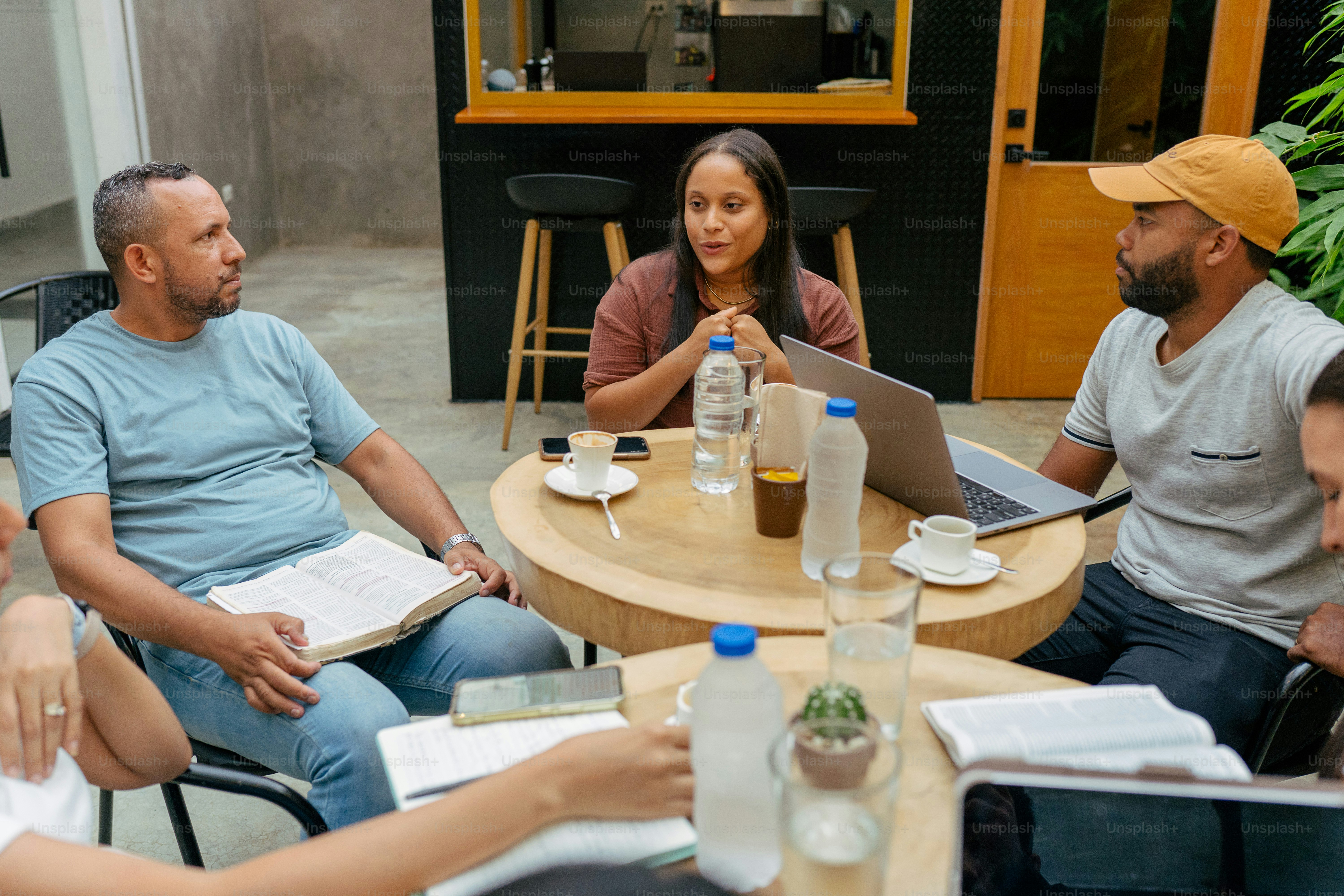 a group of people sitting around a table with laptops