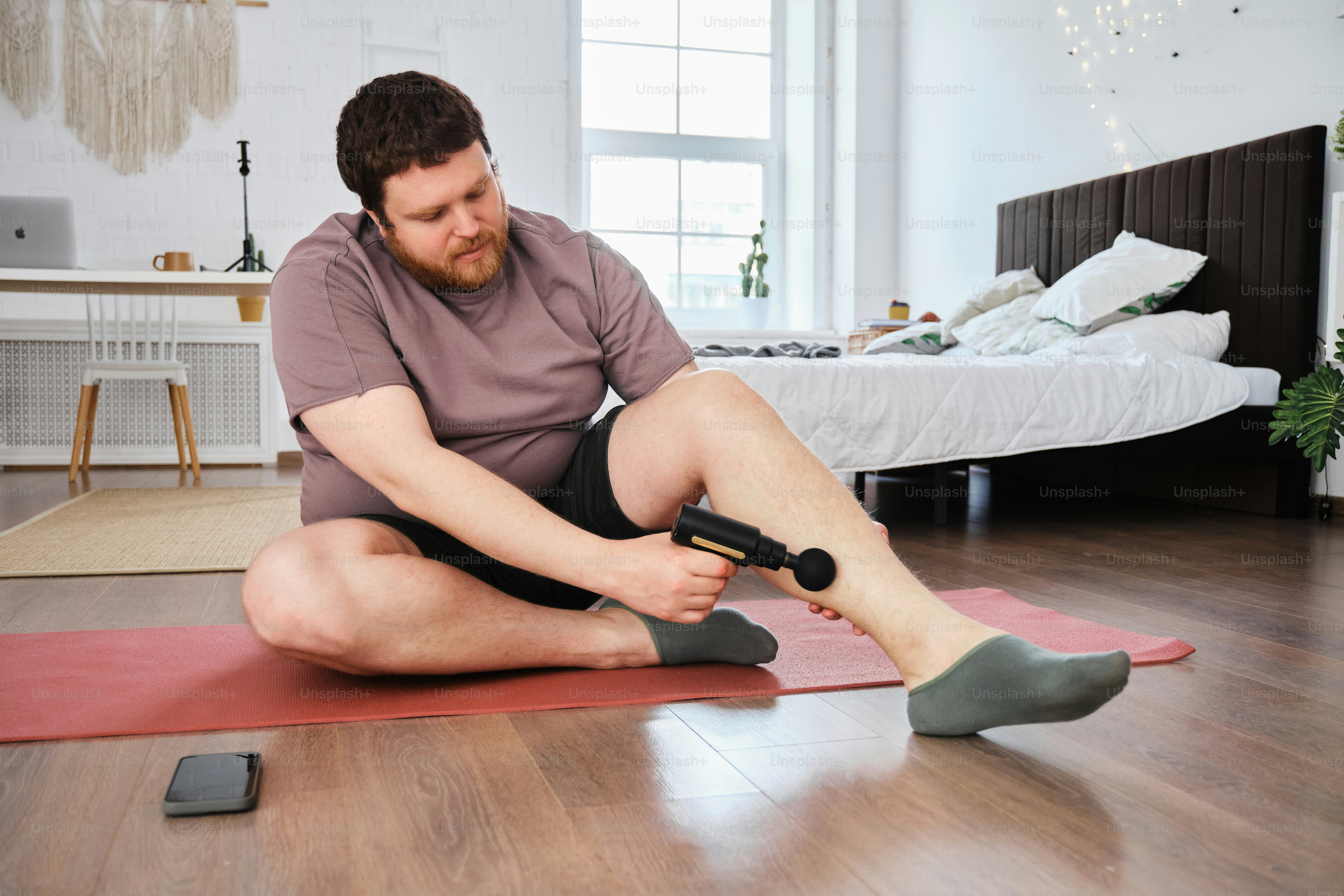 a man sitting on a yoga mat with a hair dryer in his hand