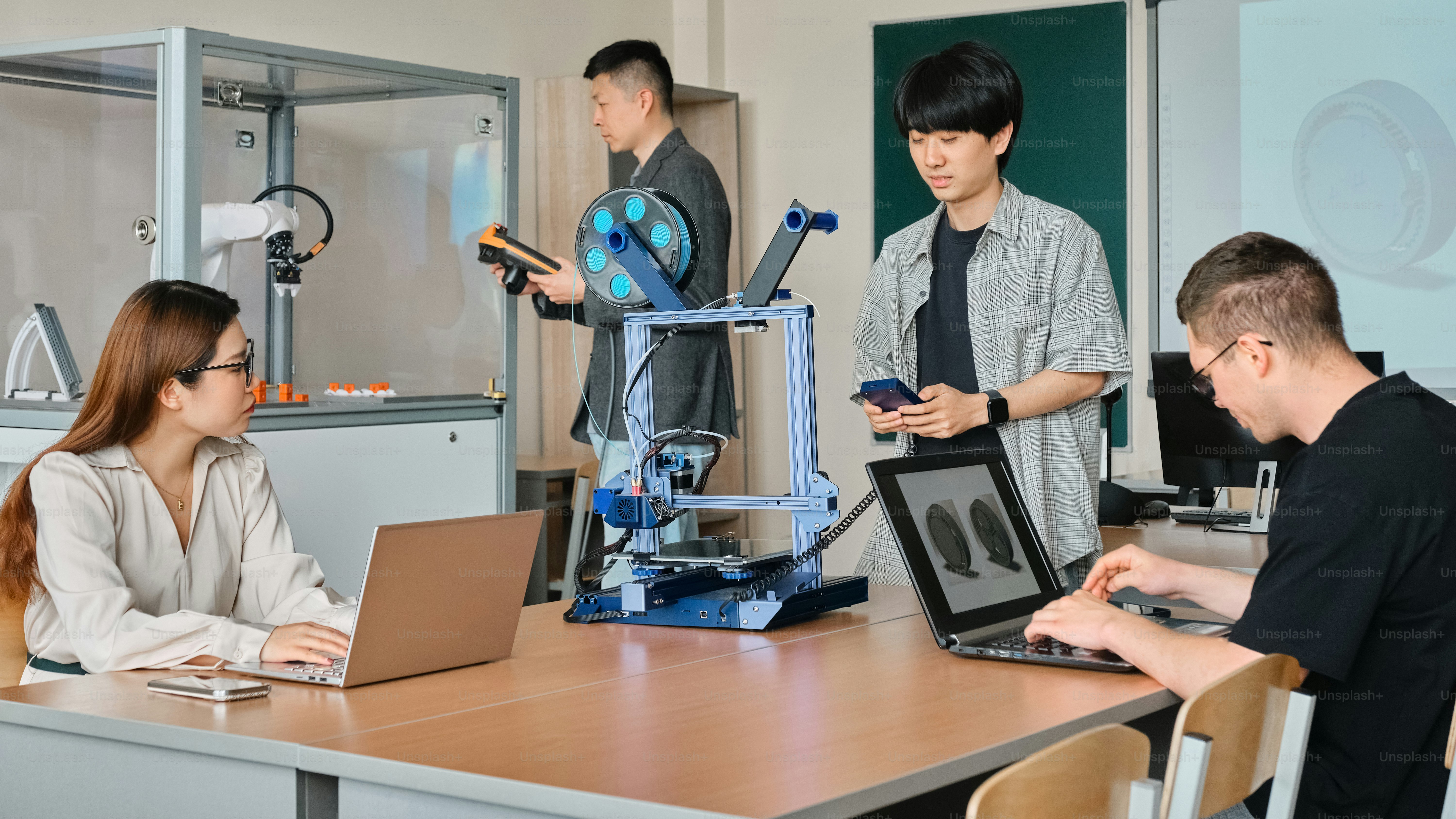 a group of people sitting around a table with laptops