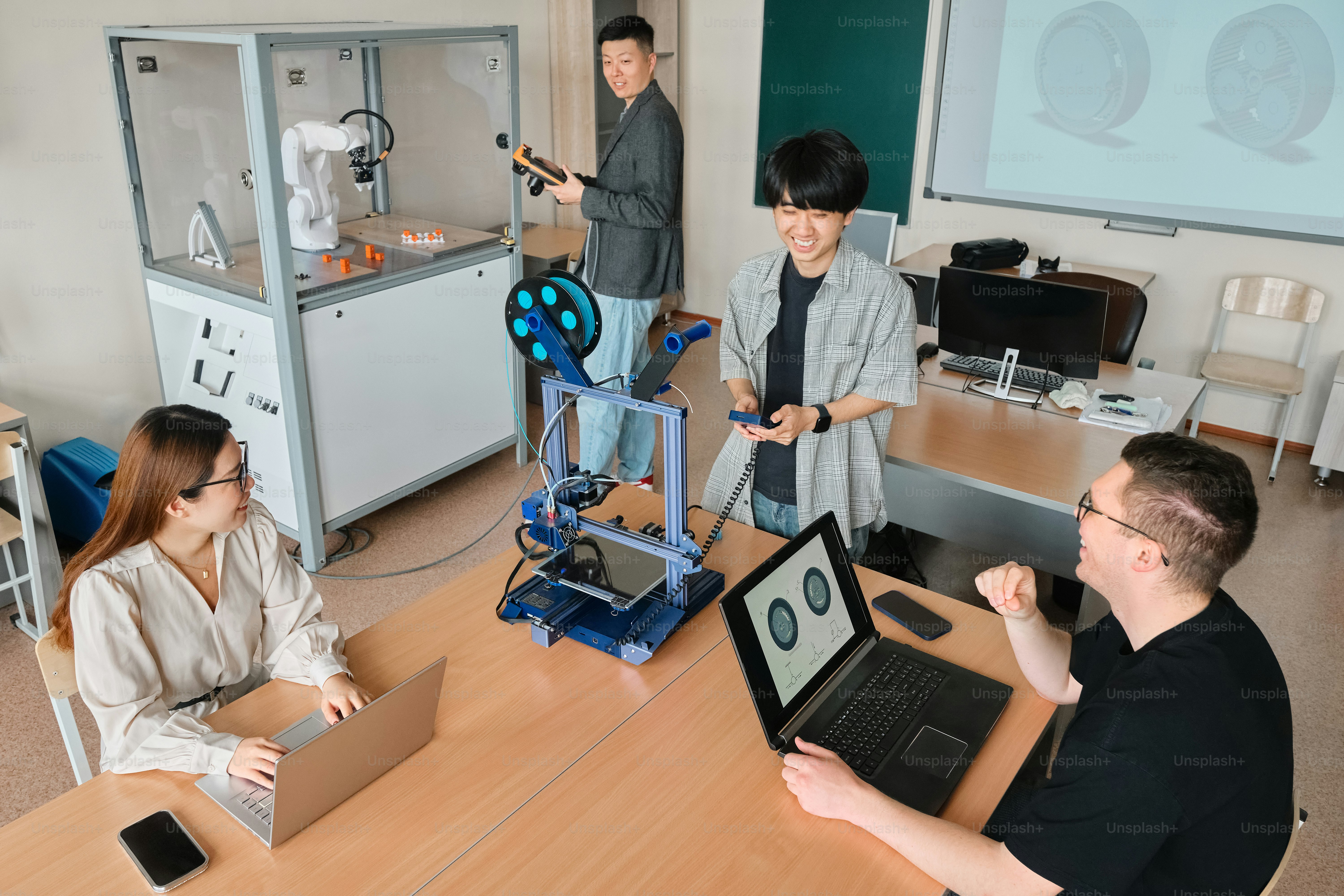 a group of people sitting around a table with laptops