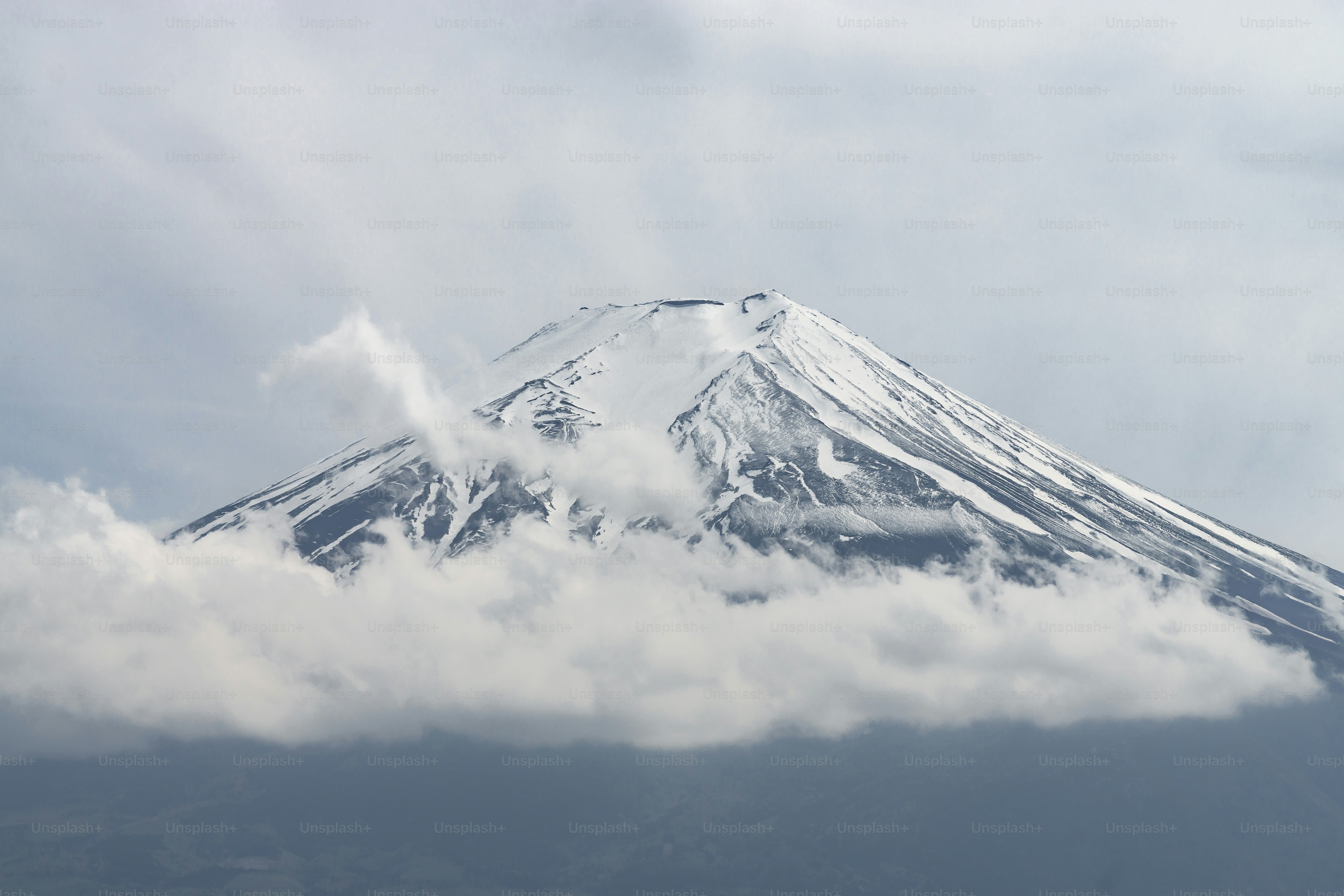 a snow covered mountain with clouds in the foreground