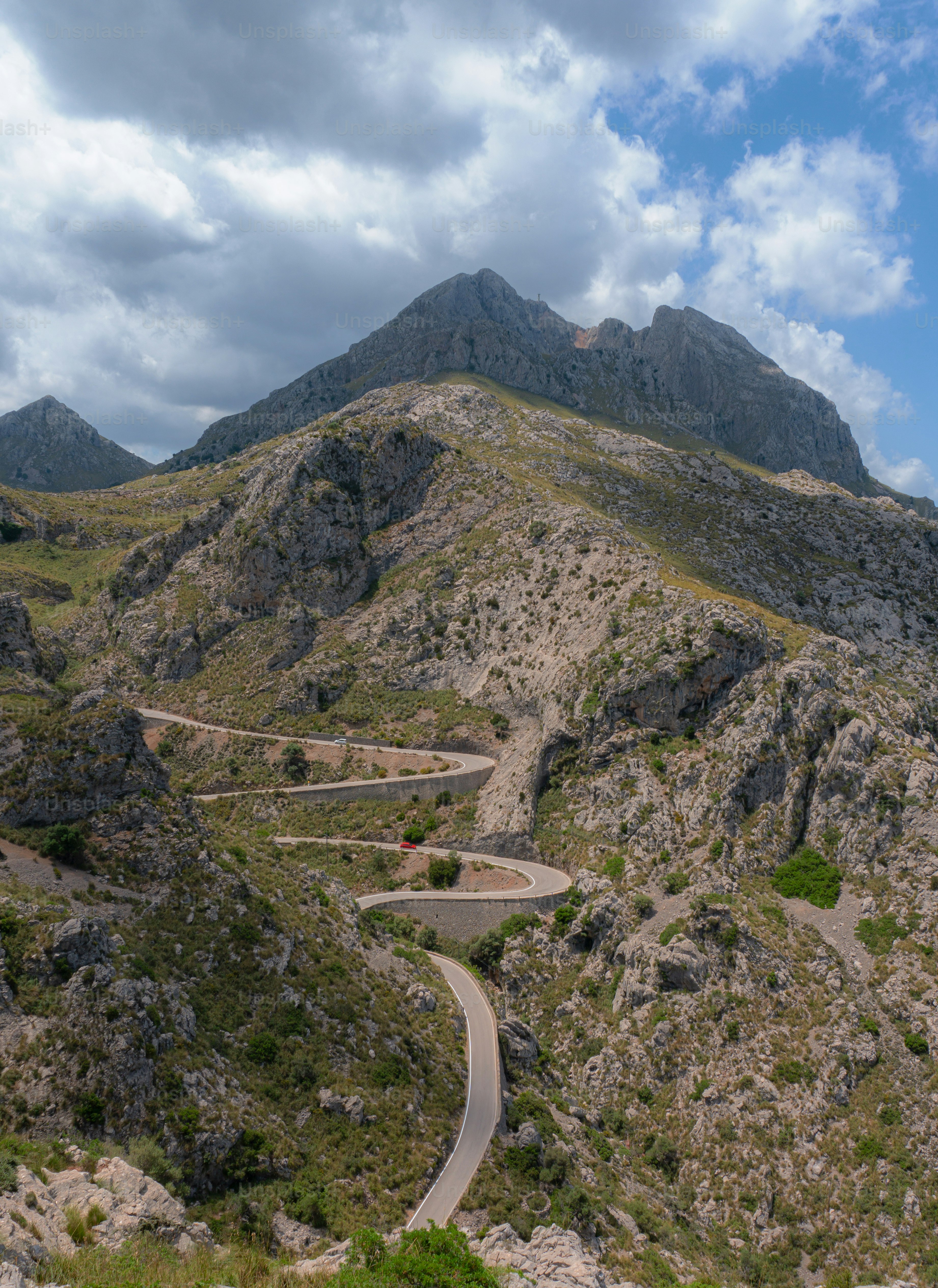 a winding road in the mountains on a cloudy day
