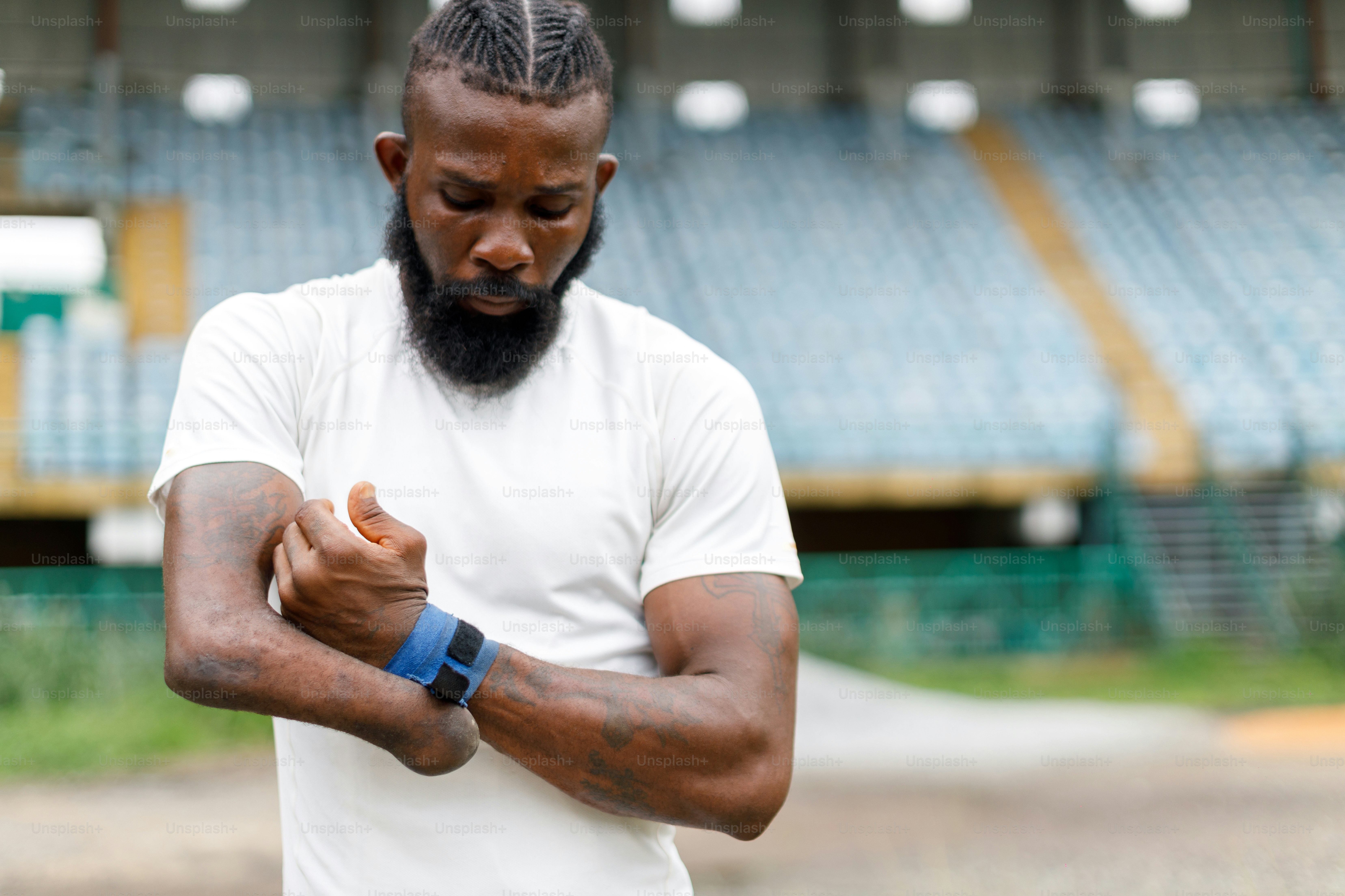 ein Mann mit Bart und weißem Hemd, der ein blaues Armband hält