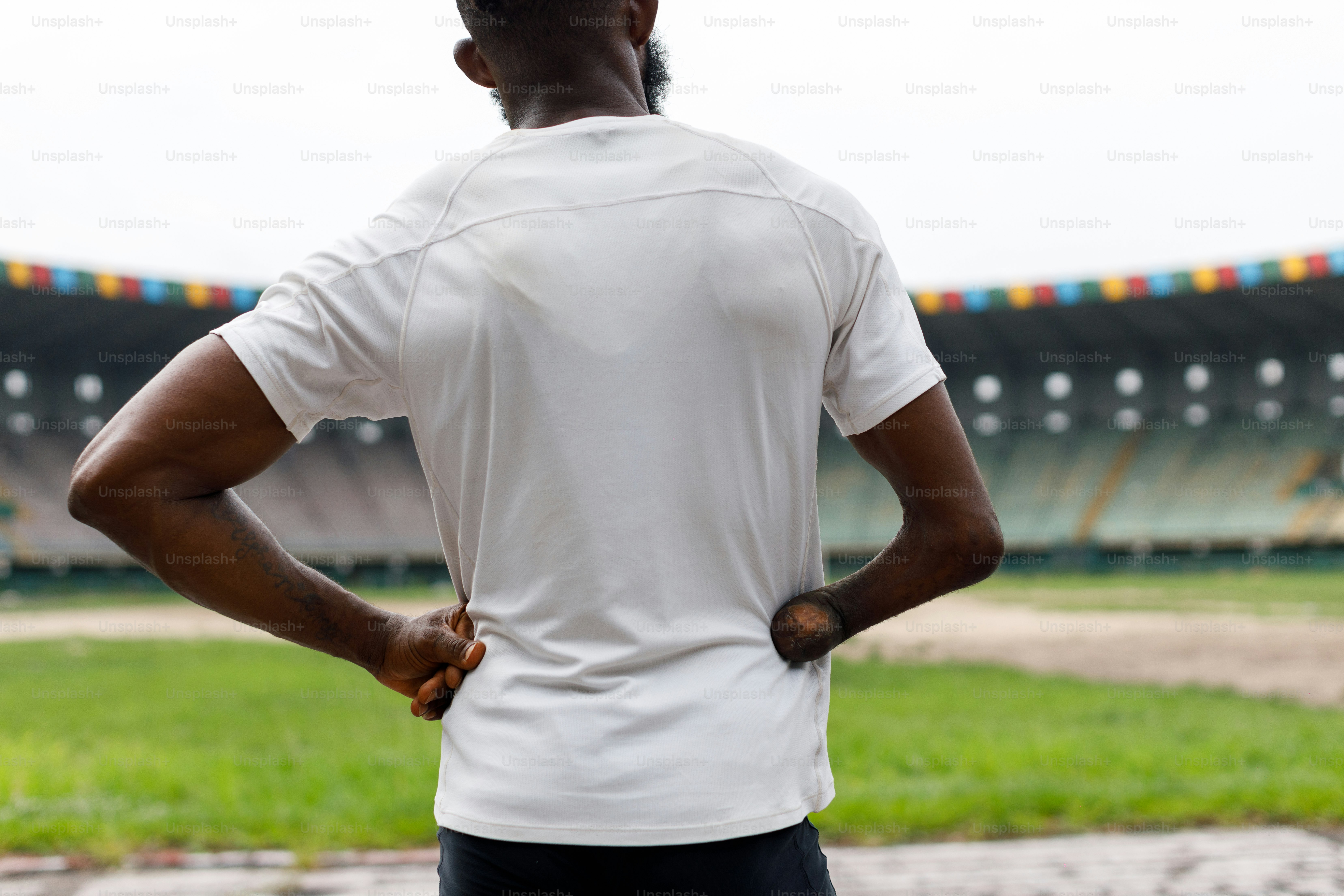 A man standing in front of a stadium with his back to the camera photo ...