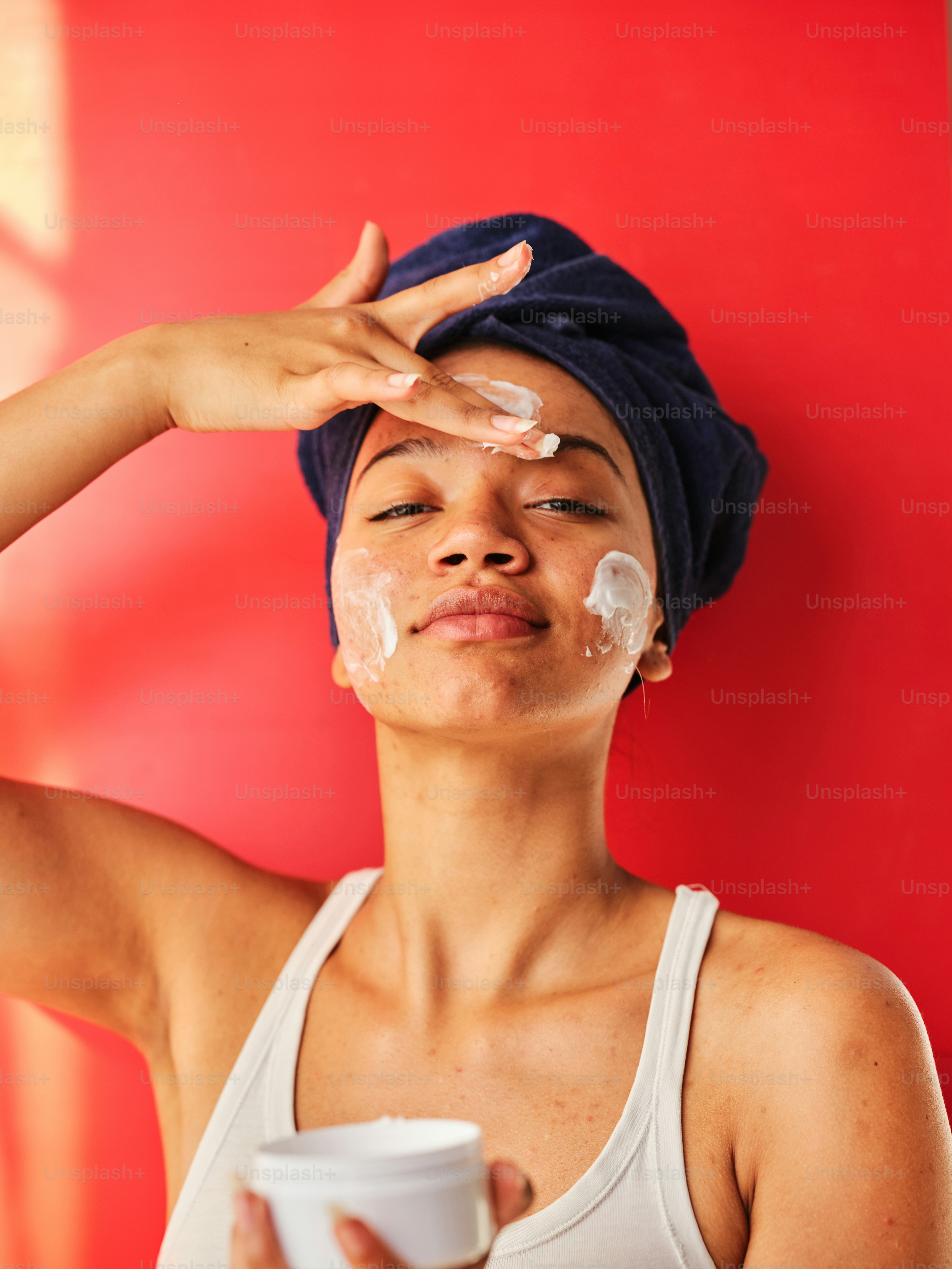 eine Frau mit einem Handtuch auf dem Kopf, die einen Becher Sahne hält