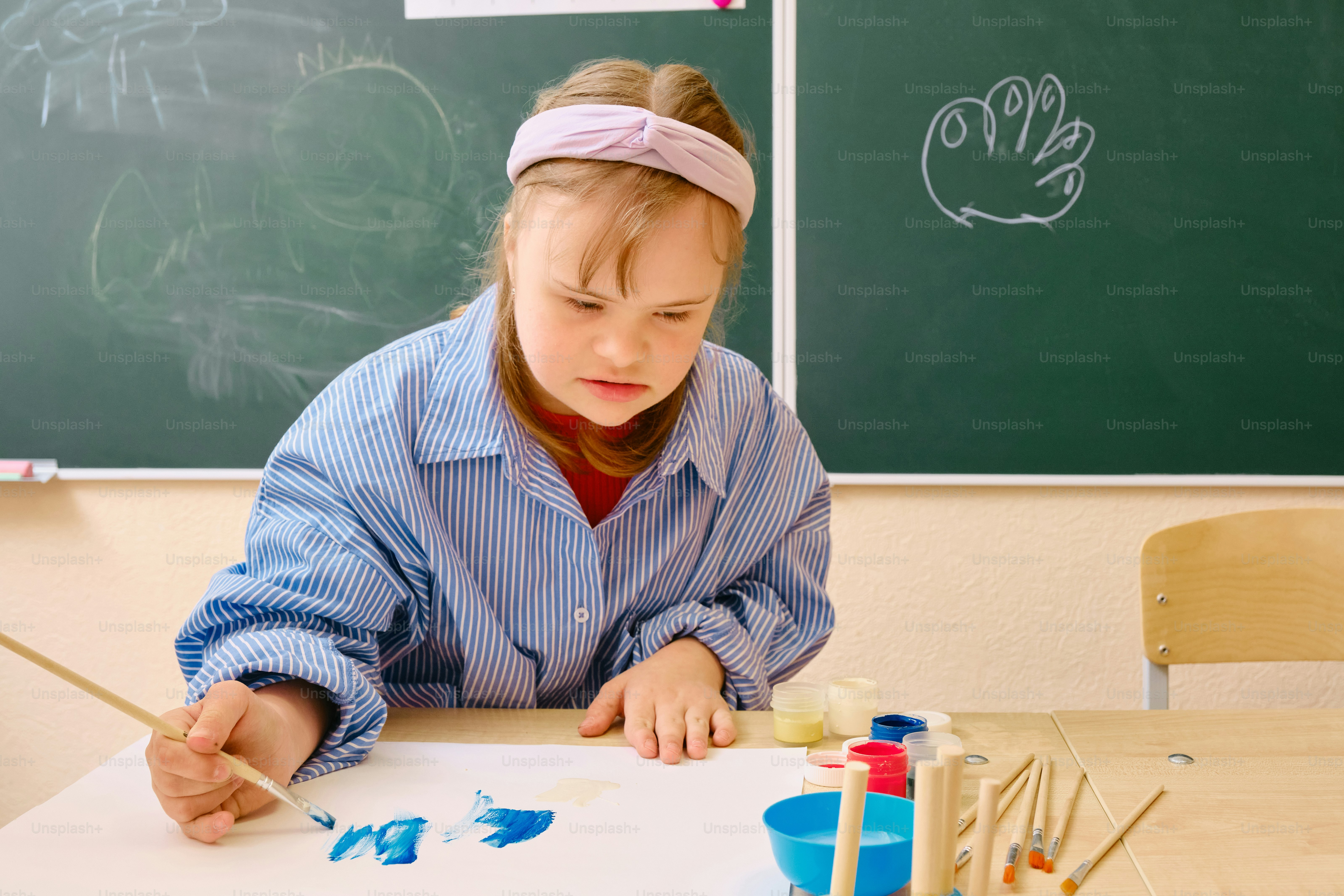 a young girl is painting in front of a blackboard