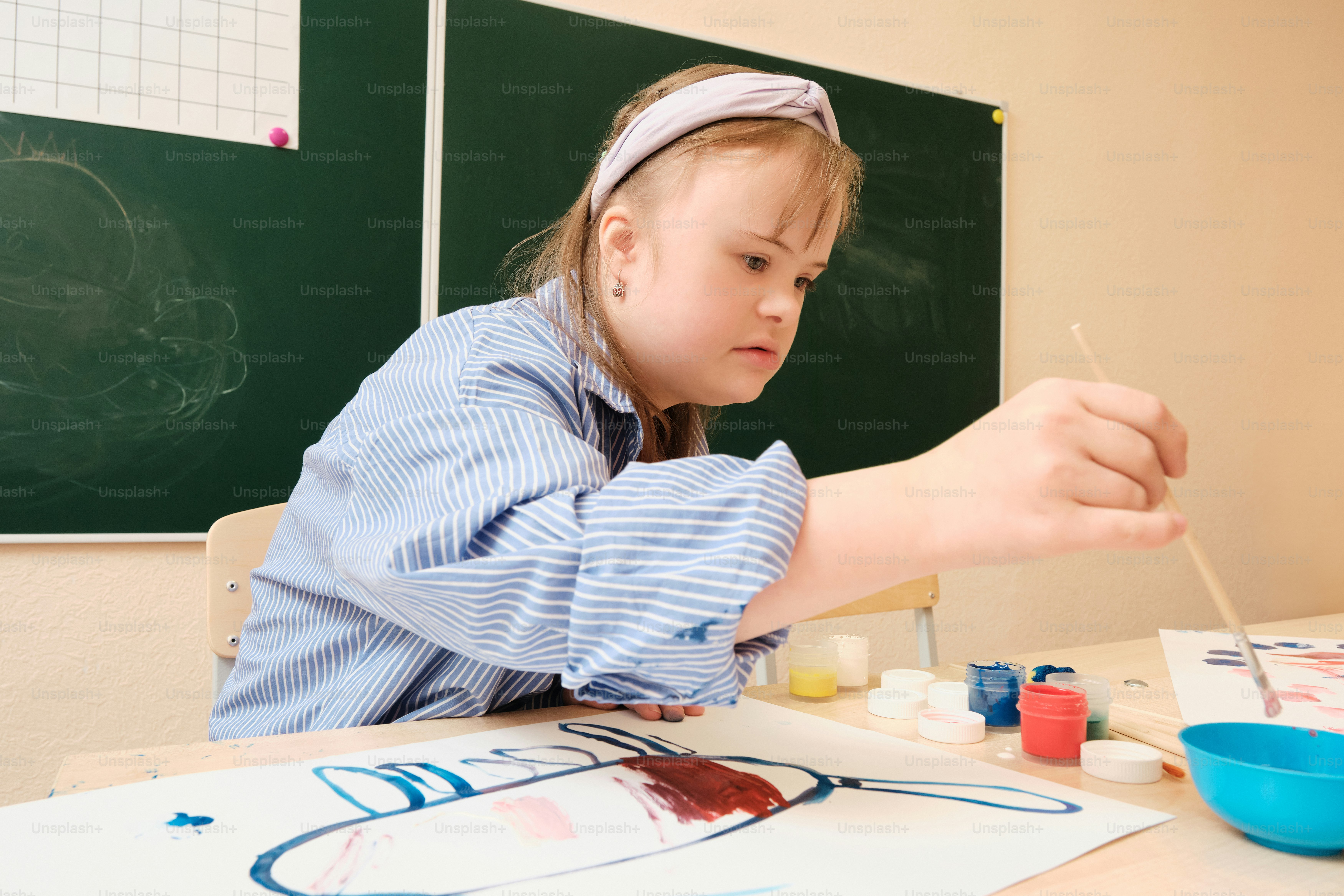 a young girl is painting on a piece of paper