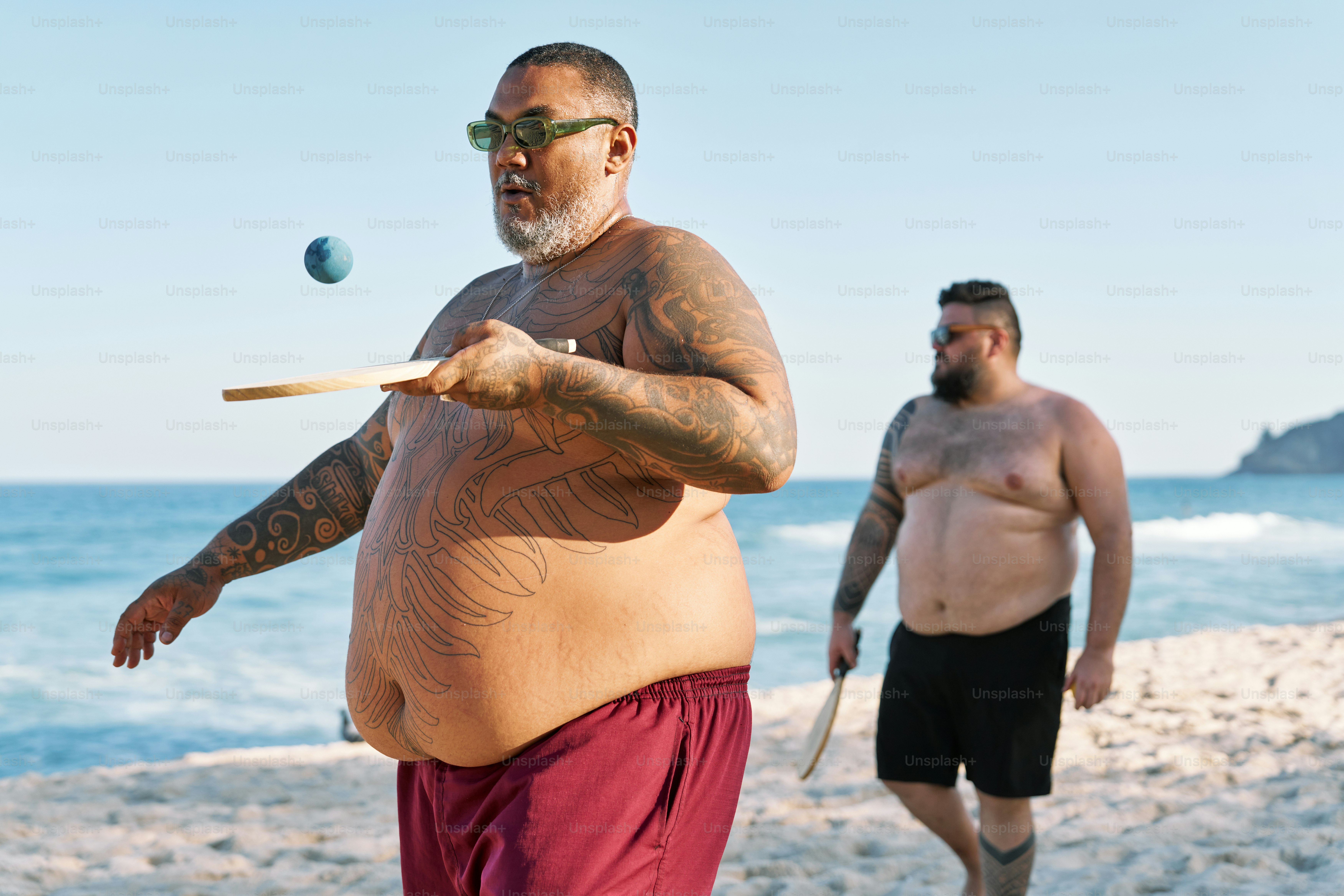 a man with a large belly playing a game of croquet on the beach