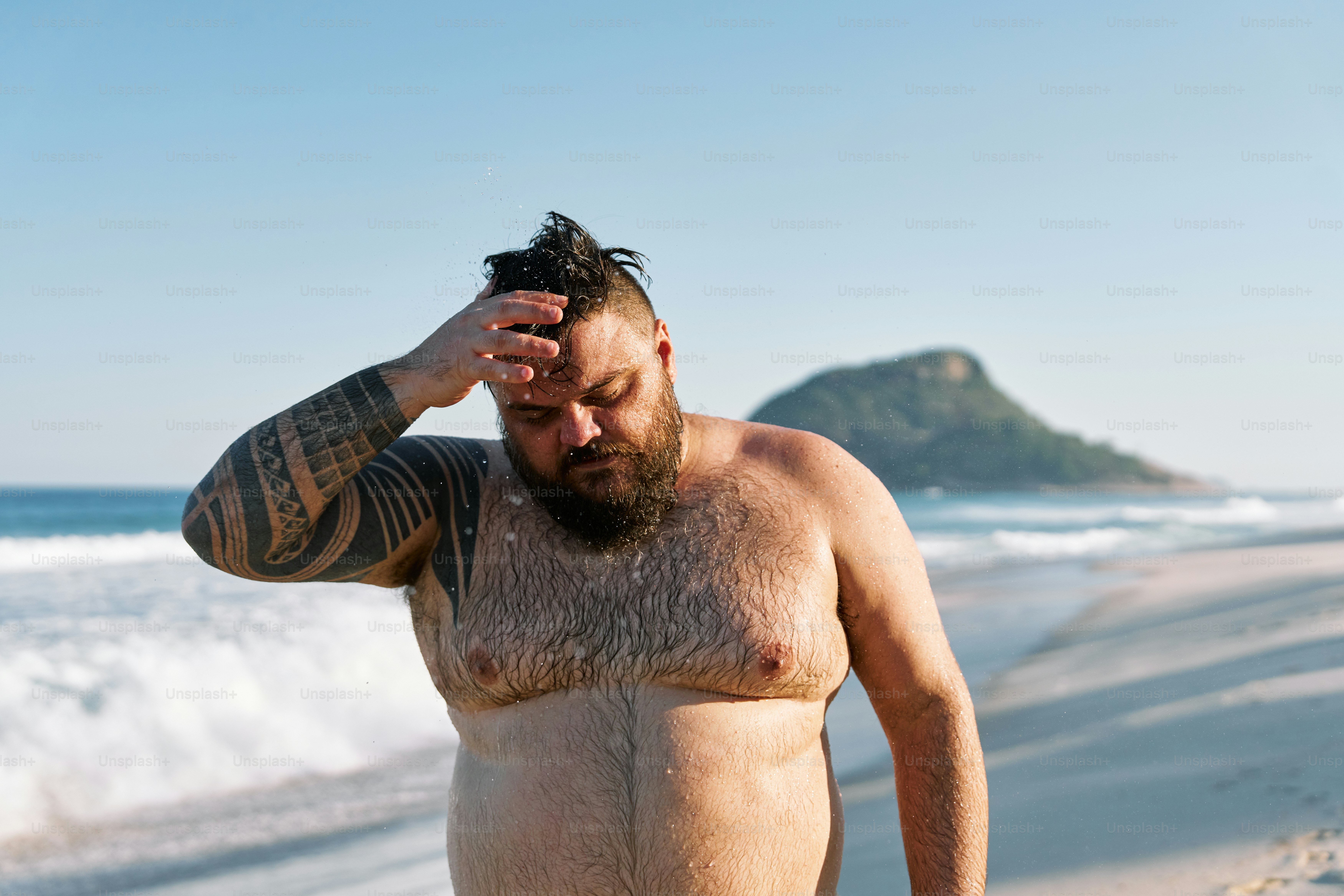 a man with no shirt on standing on the beach