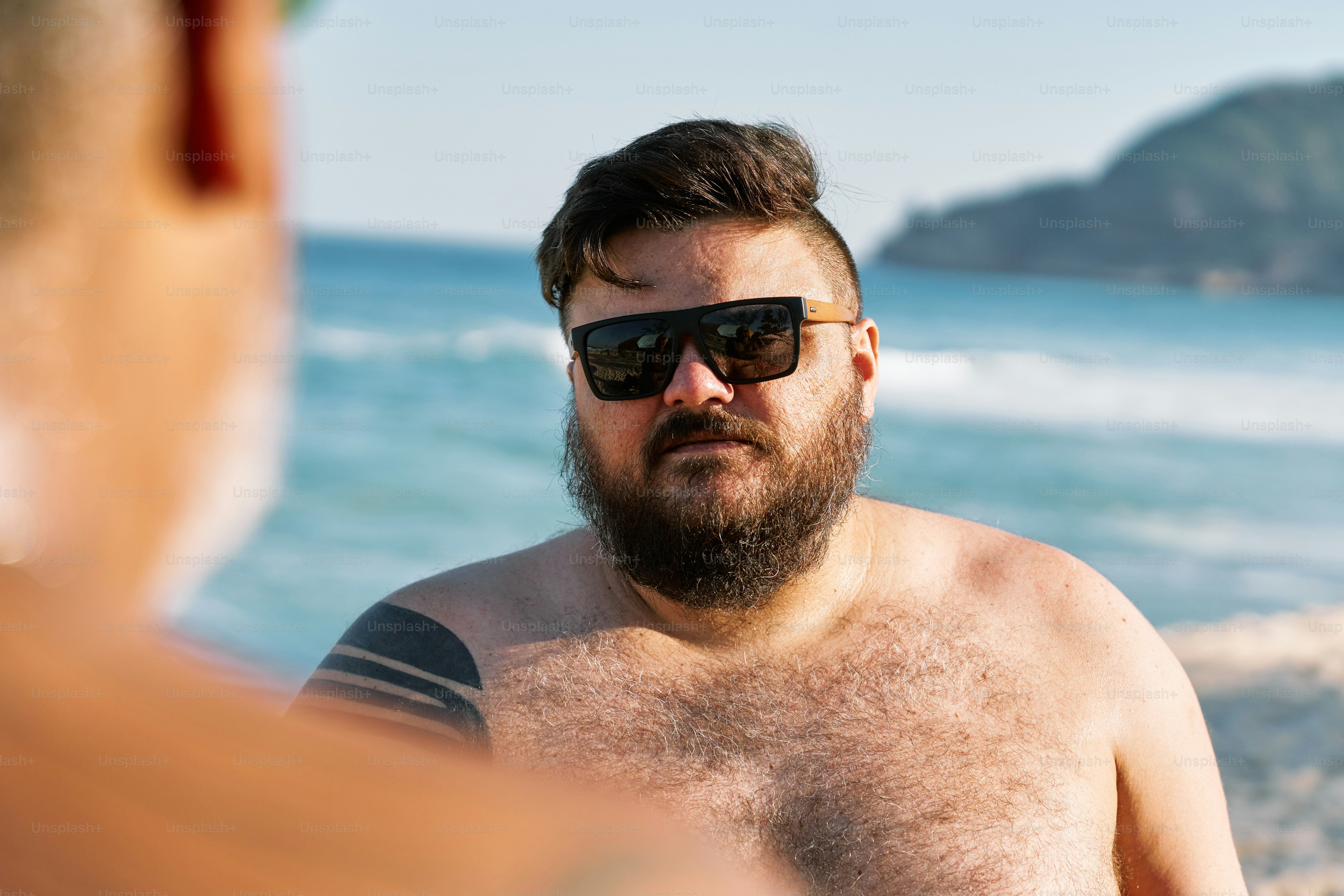 a man with sunglasses on sitting on the beach