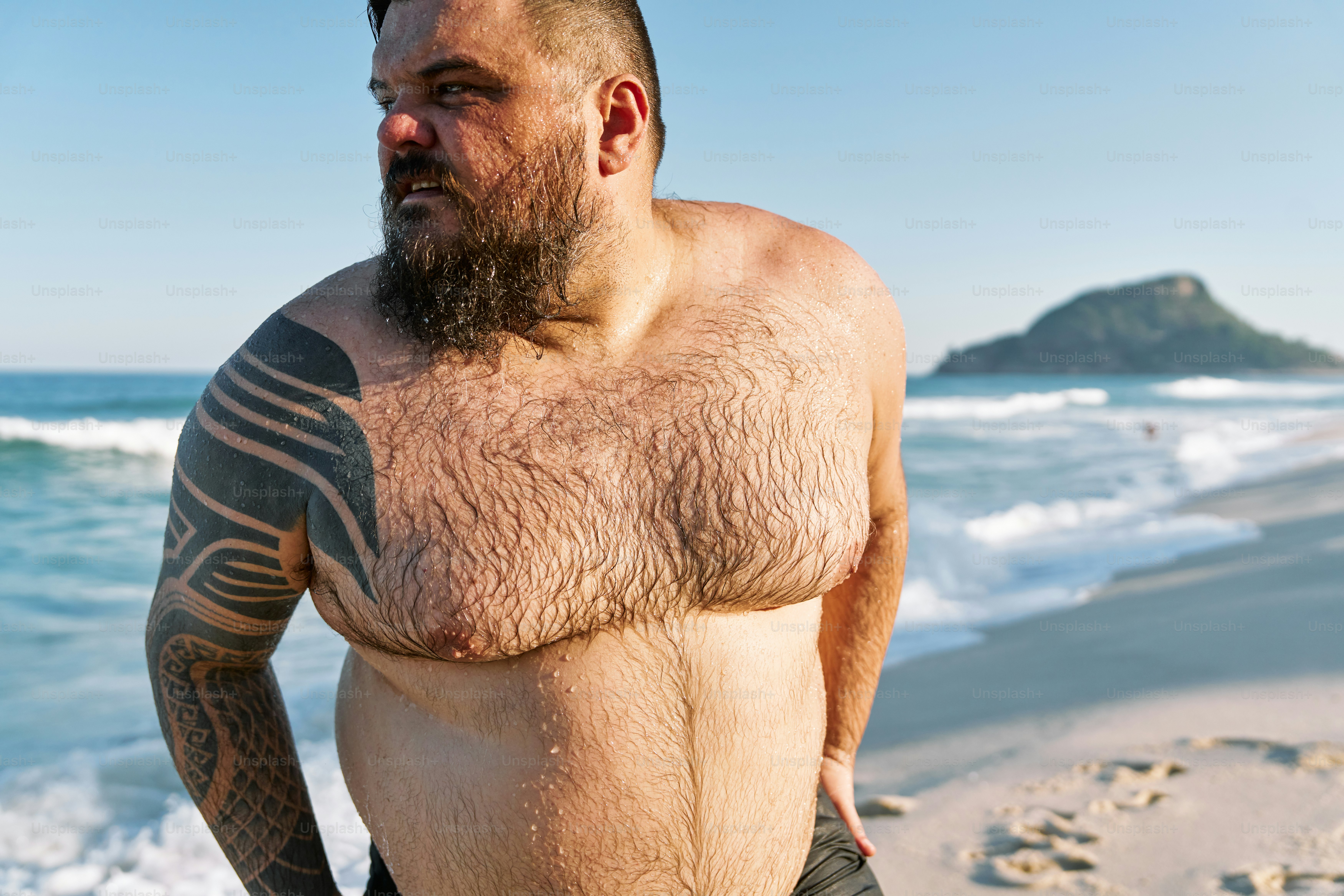 a man with a beard standing on the beach