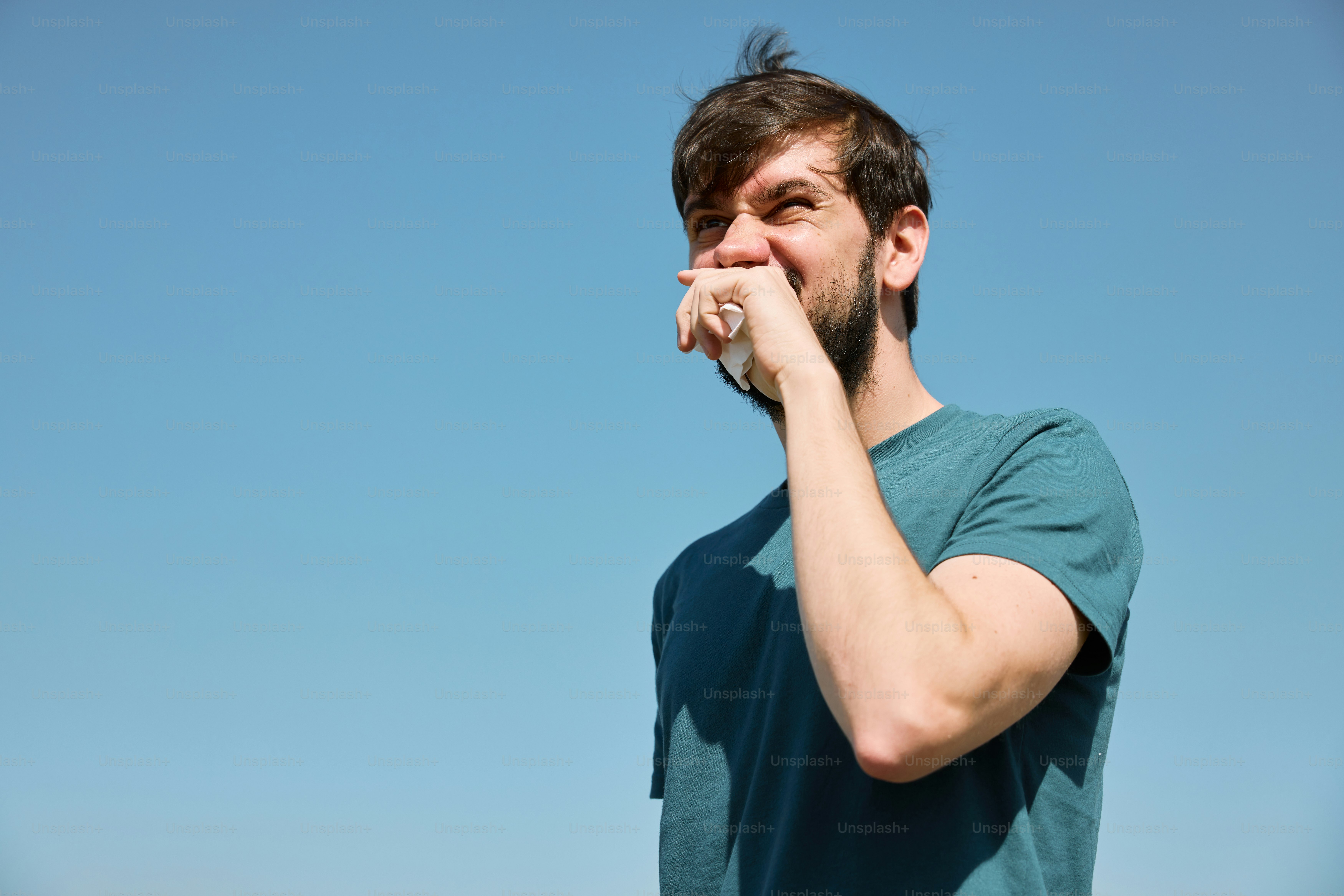 a man with a beard is holding his hand to his mouth