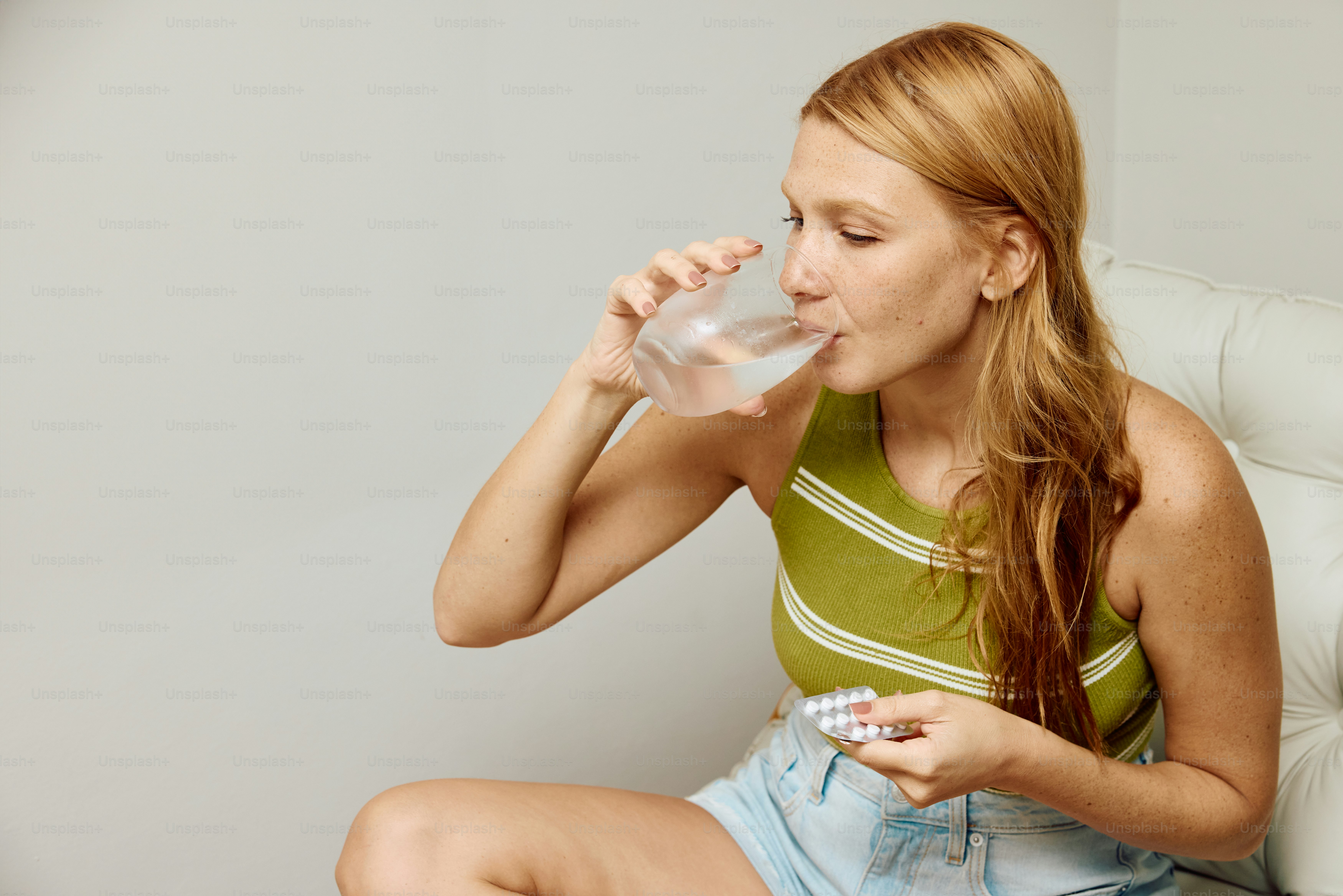 a woman sitting on a chair drinking a glass of water
