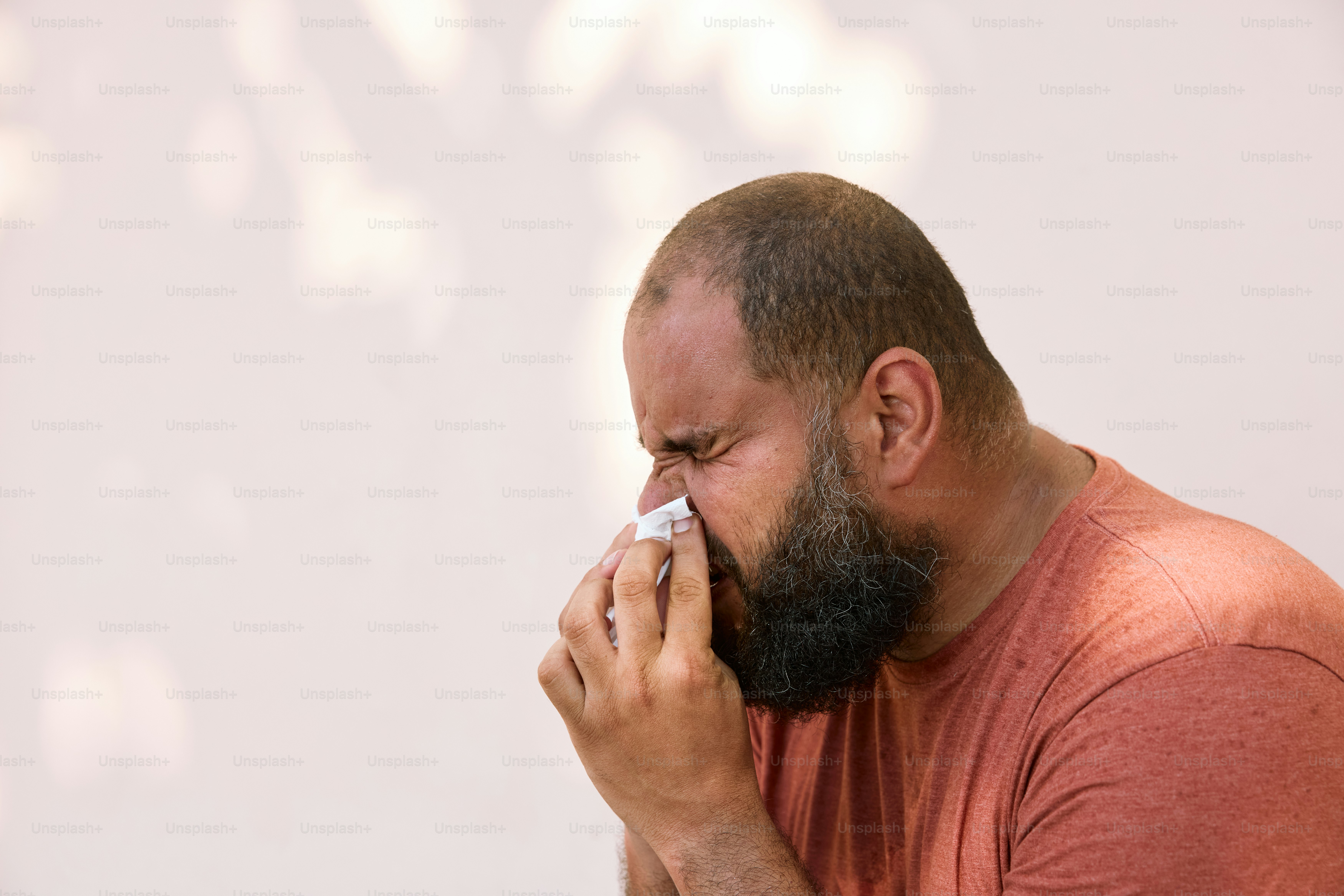 Un hombre con barba se suena la nariz