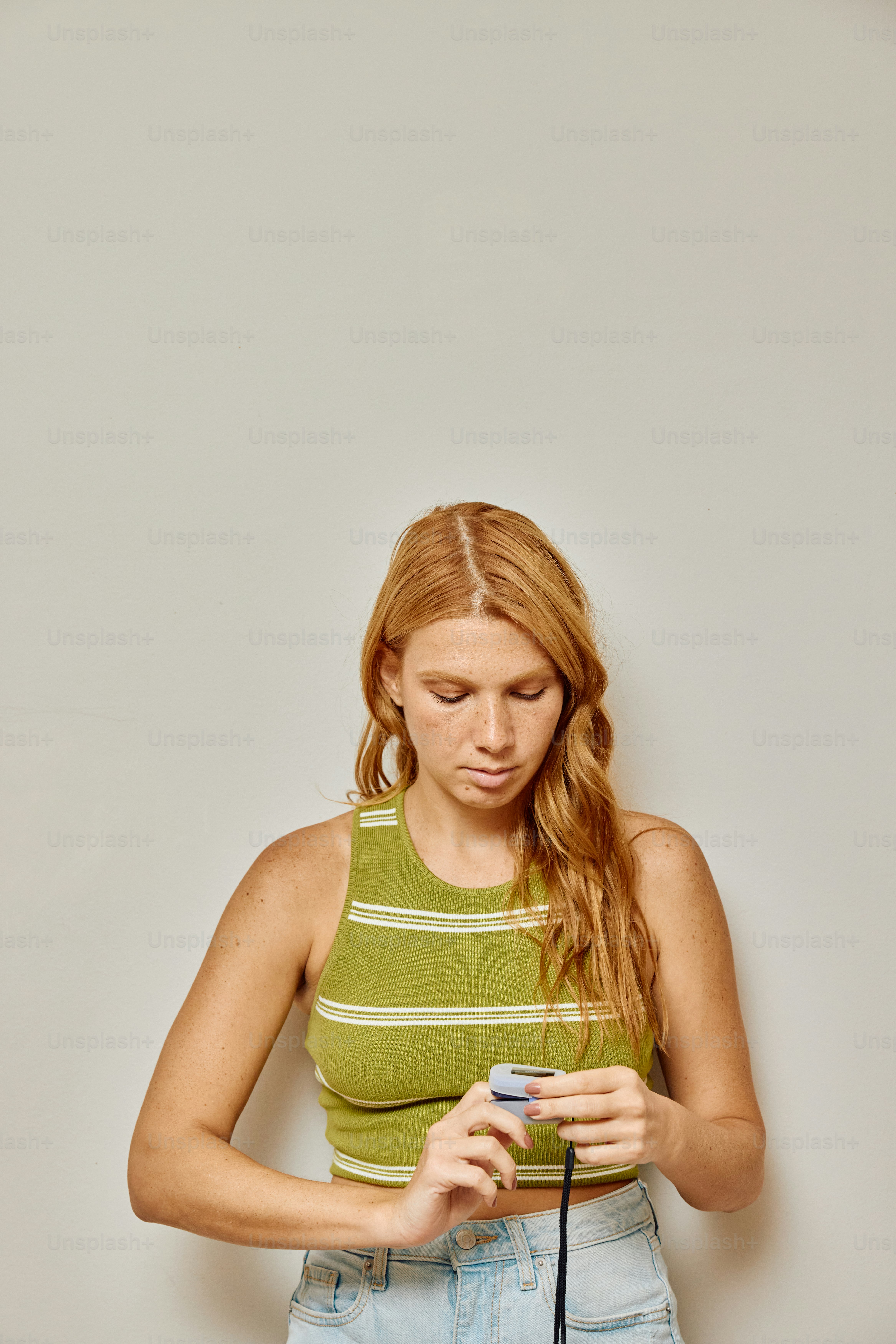 a woman in a green tank top holding a cell phone
