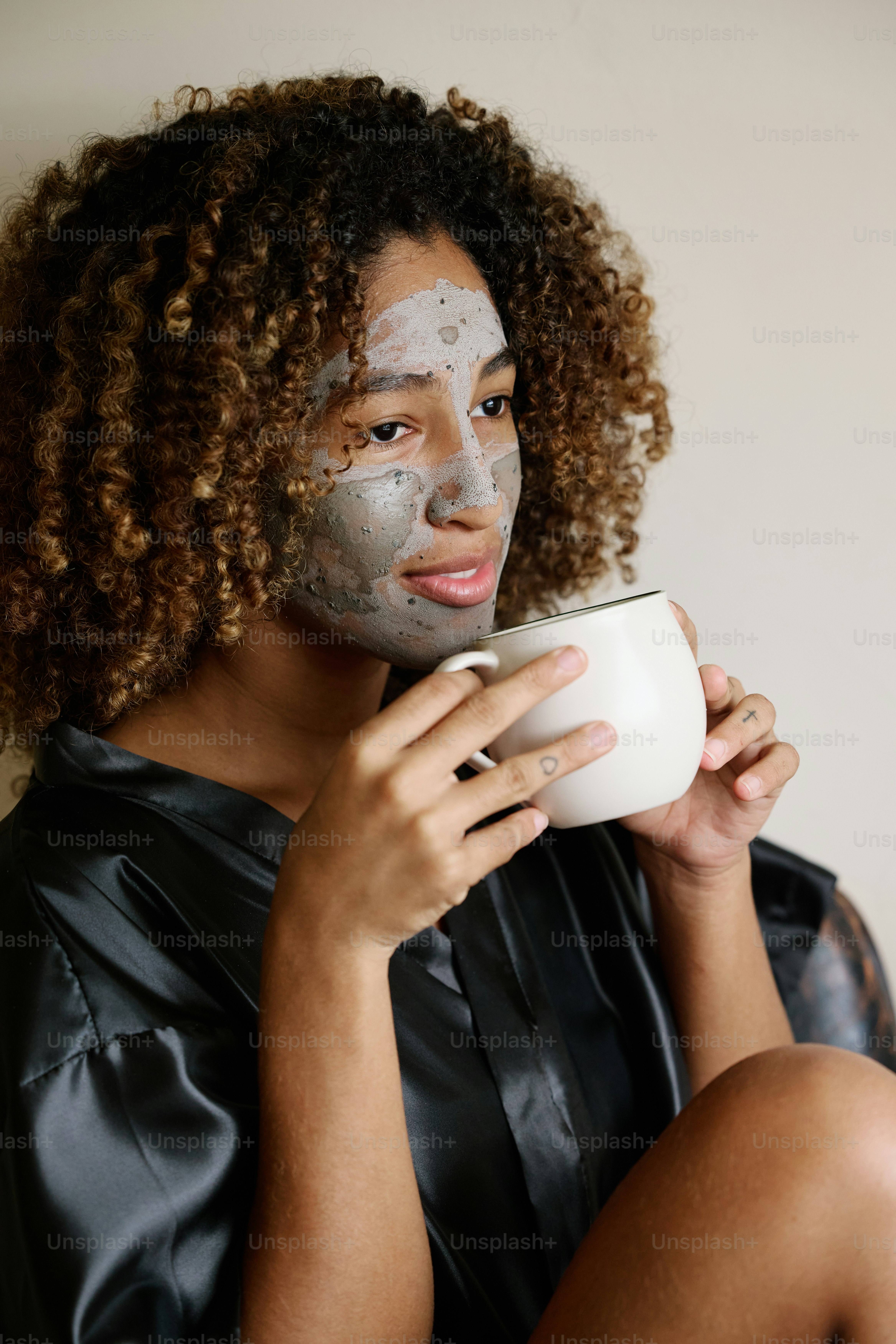 une femme avec un masque facial tenant une tasse