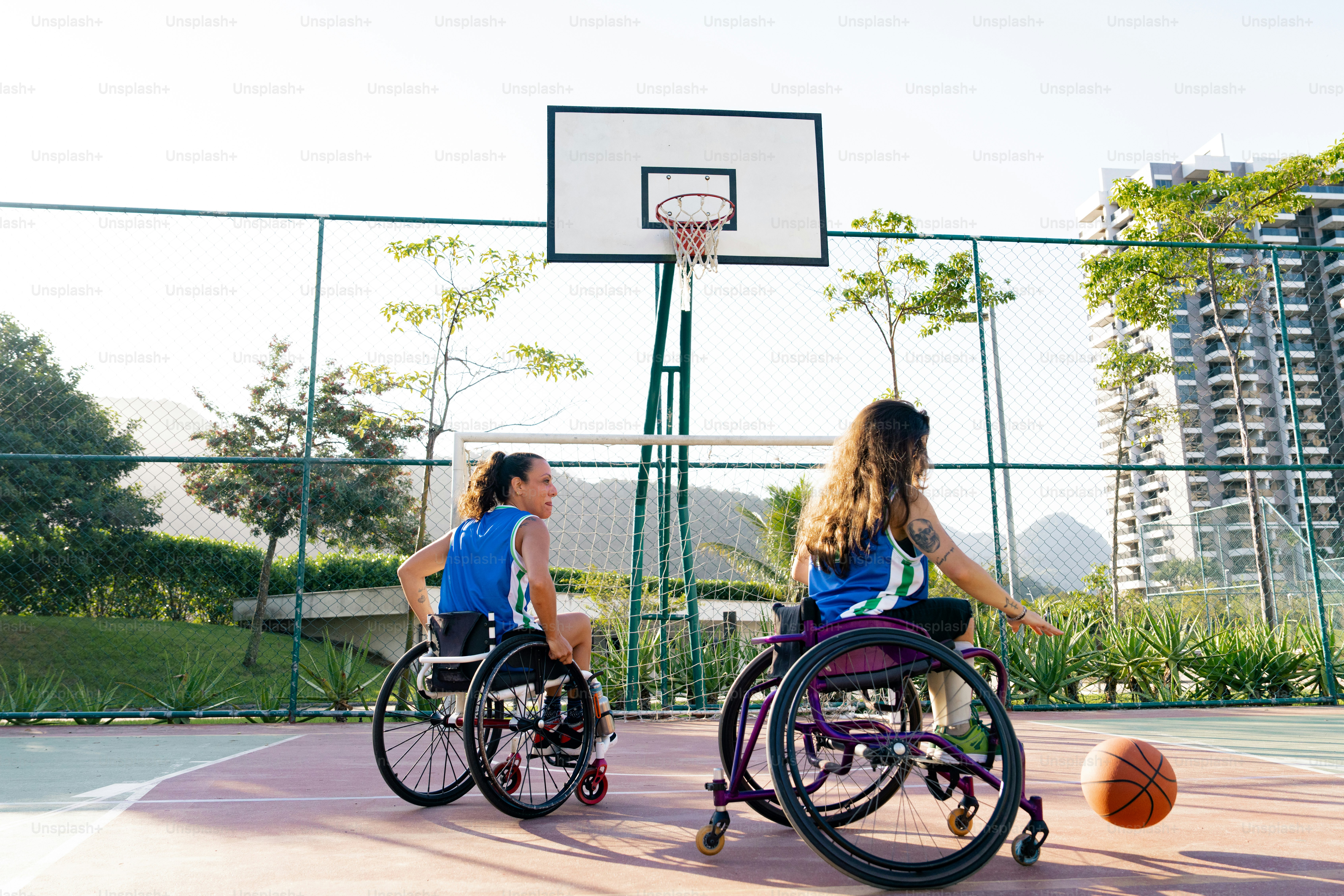 Zwei Frauen im Rollstuhl spielen Basketball auf einem Spielfeld
