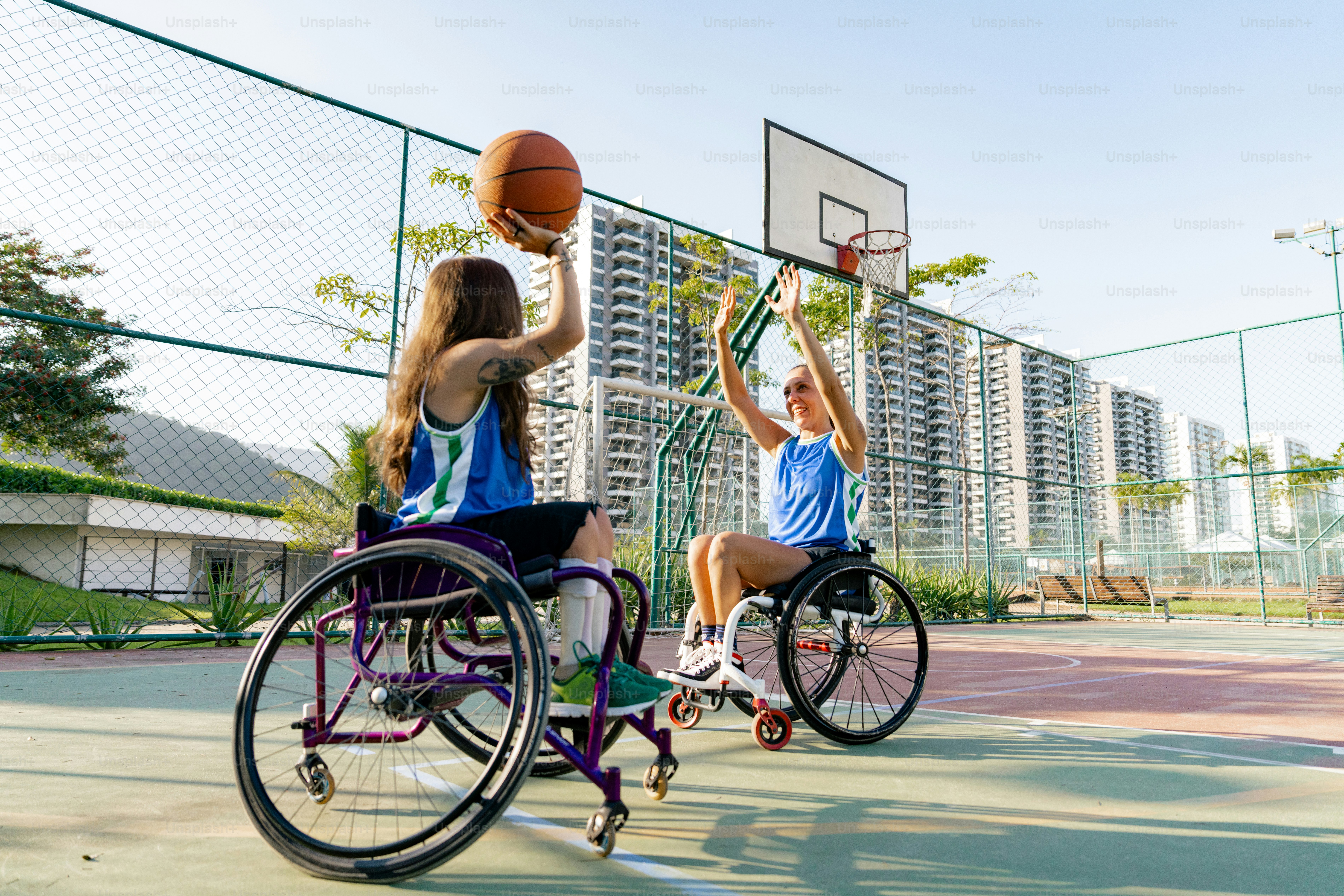 two people in wheelchairs playing basketball on a court