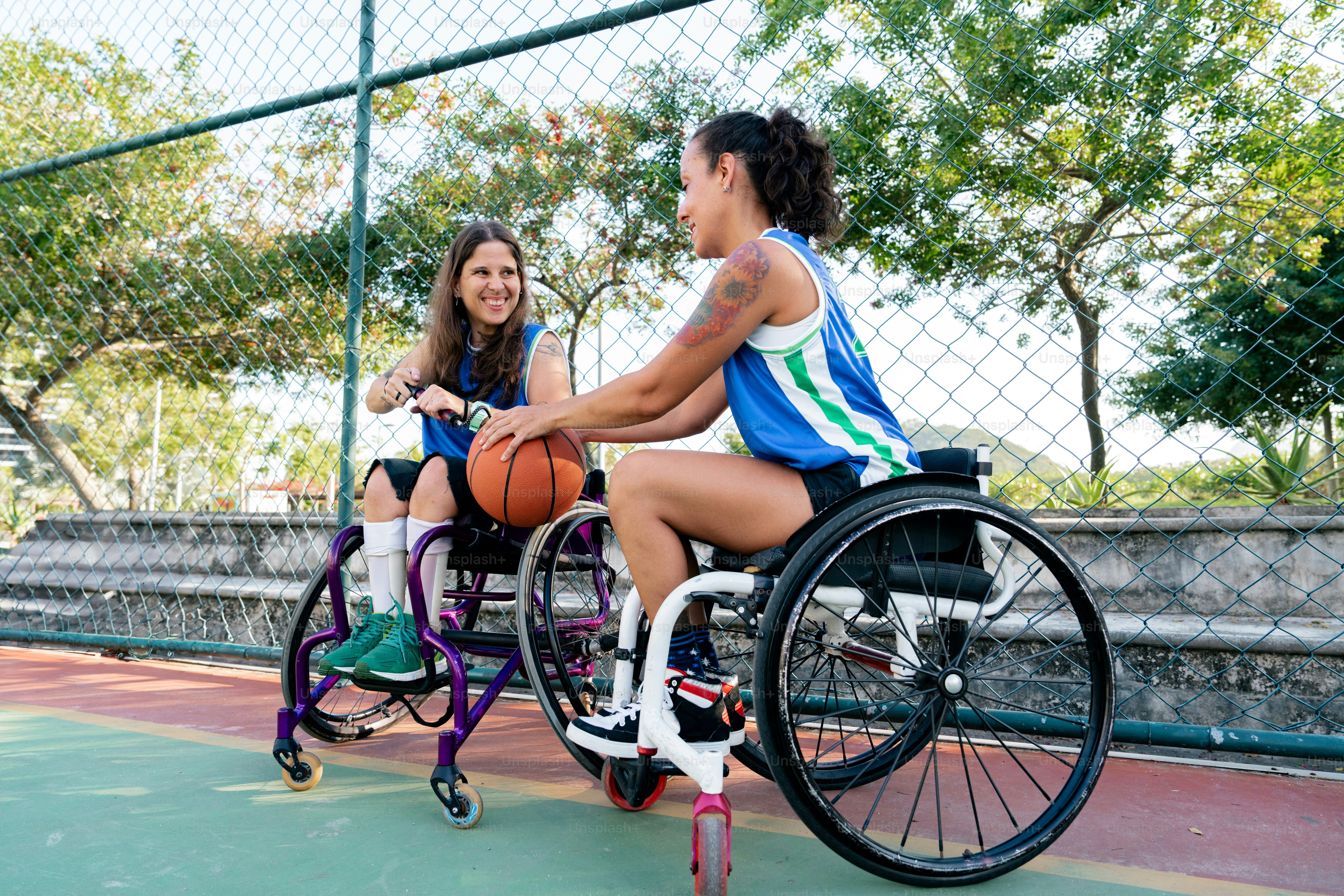 Zwei Mädchen im Rollstuhl spielen Basketball auf einem Platz