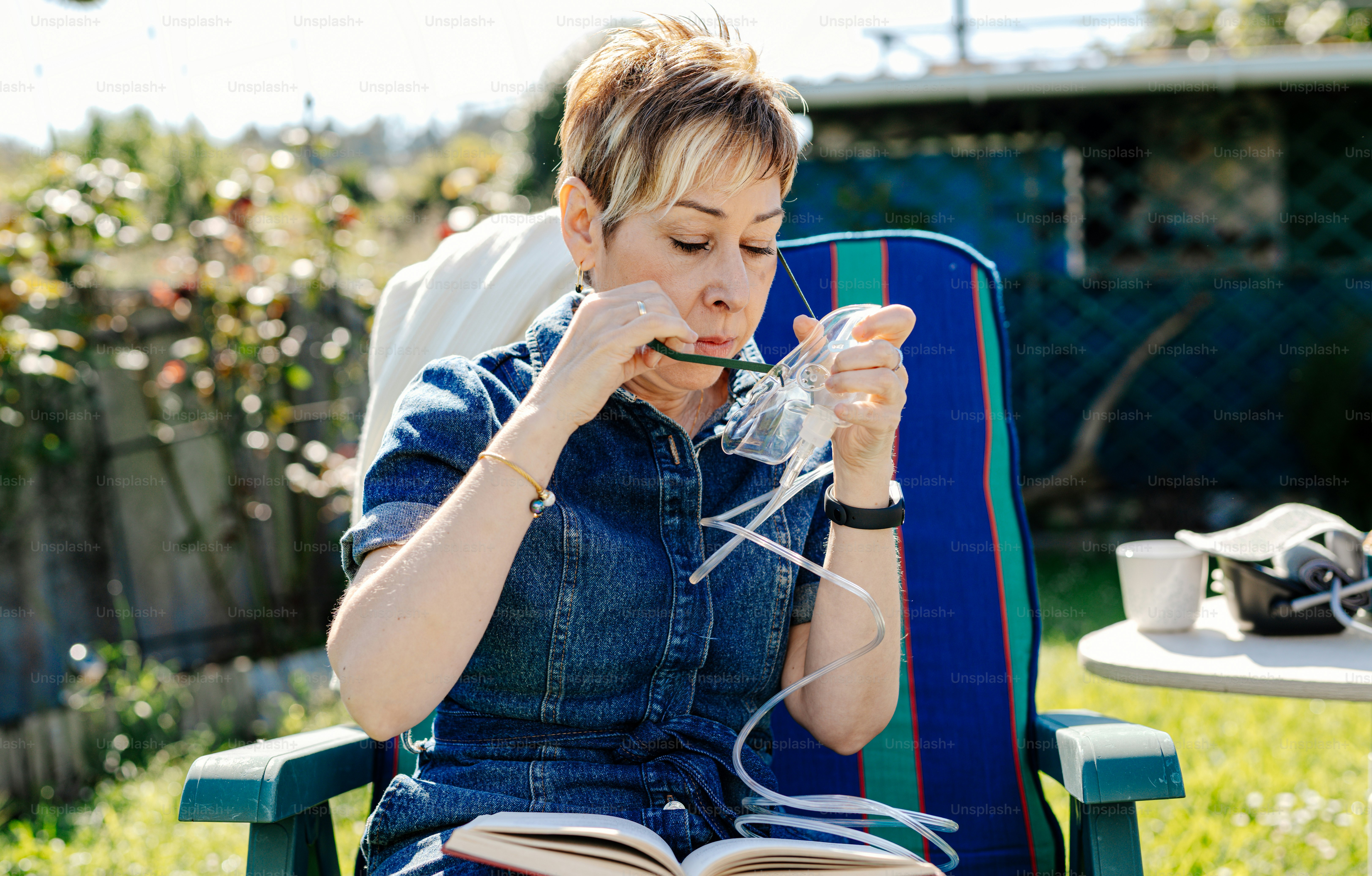 una mujer sentada en una silla de jardín leyendo un libro