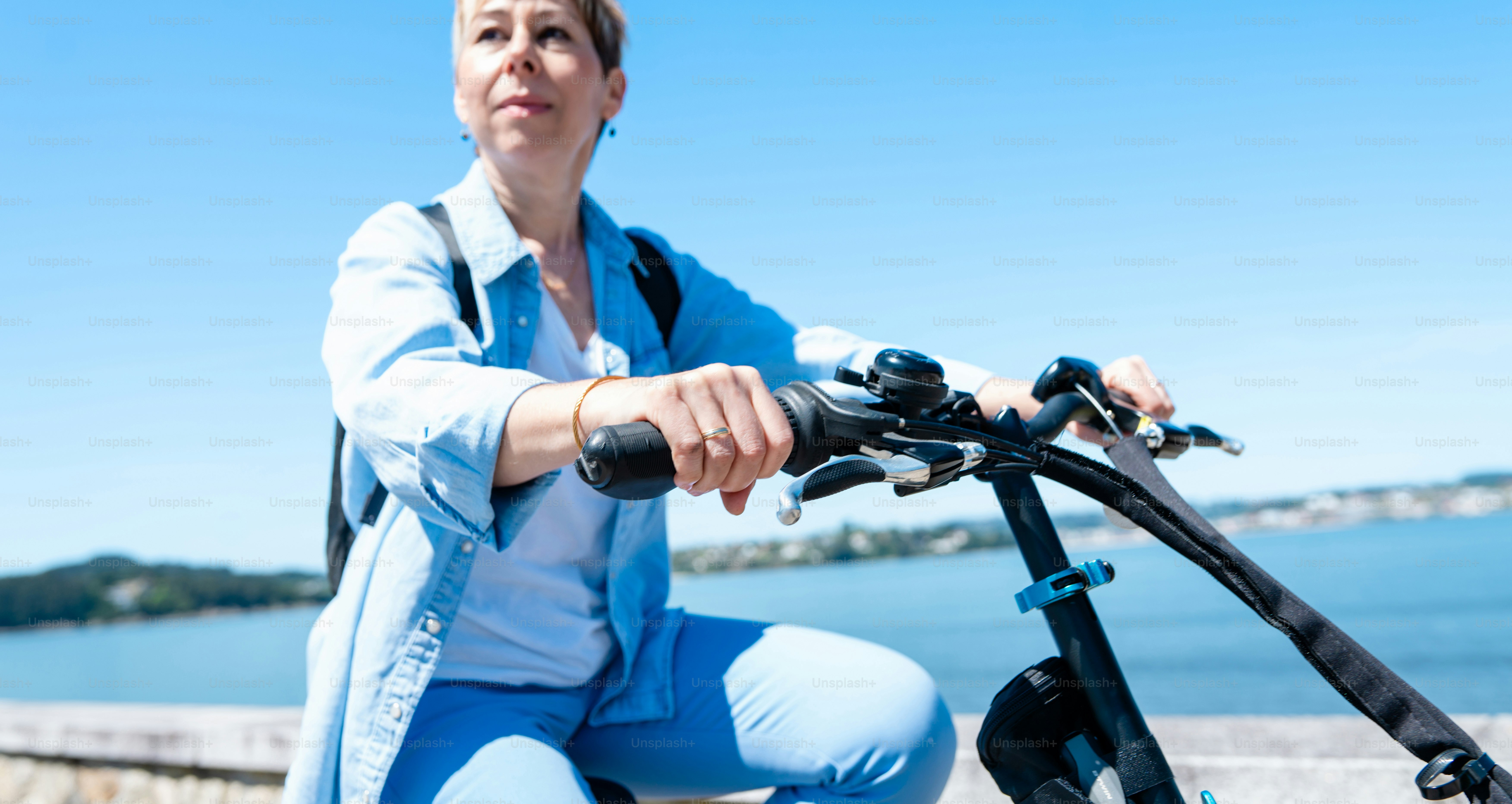 a woman sitting on a bike next to a body of water