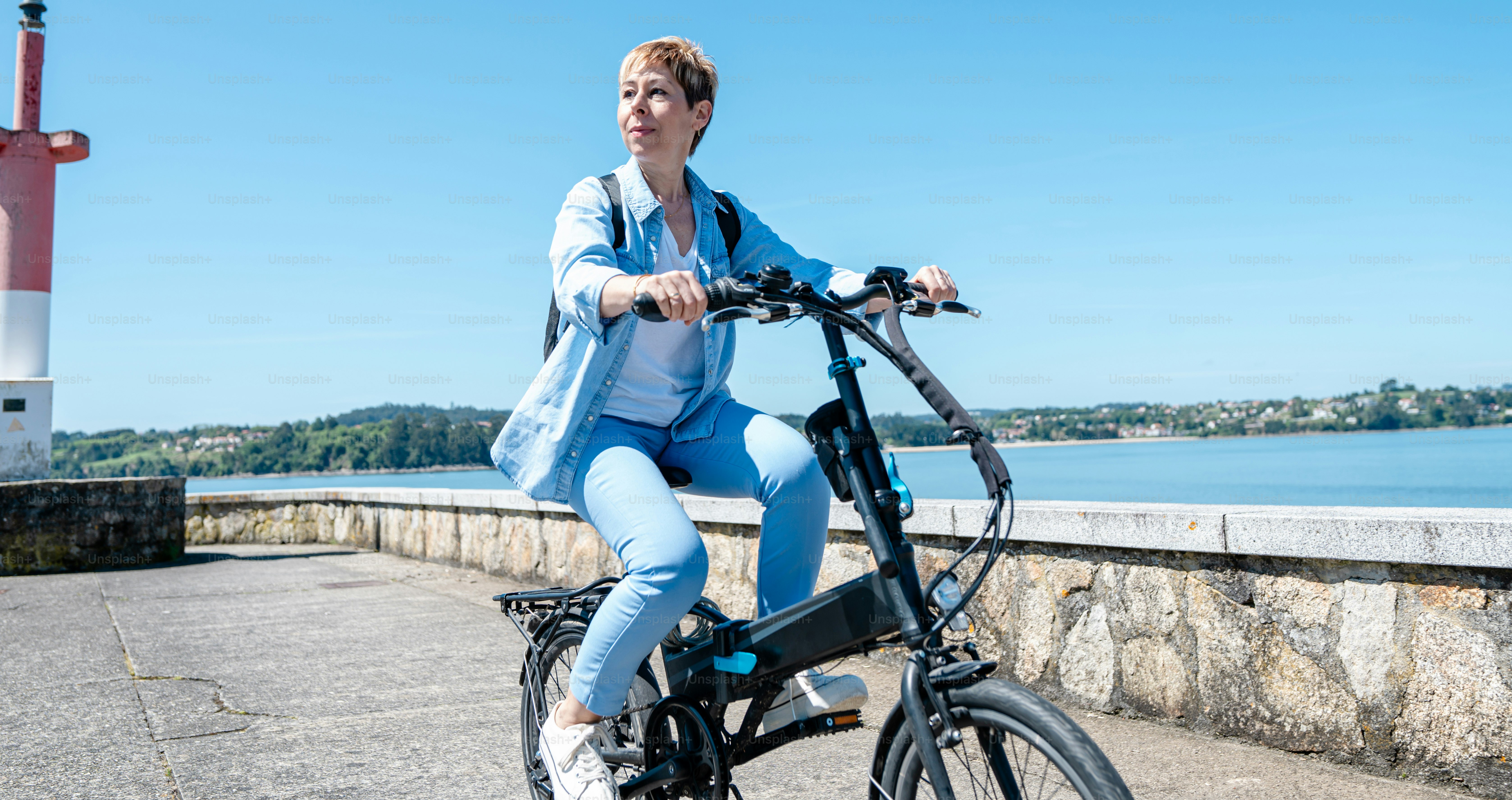 a woman is riding a bike near the water