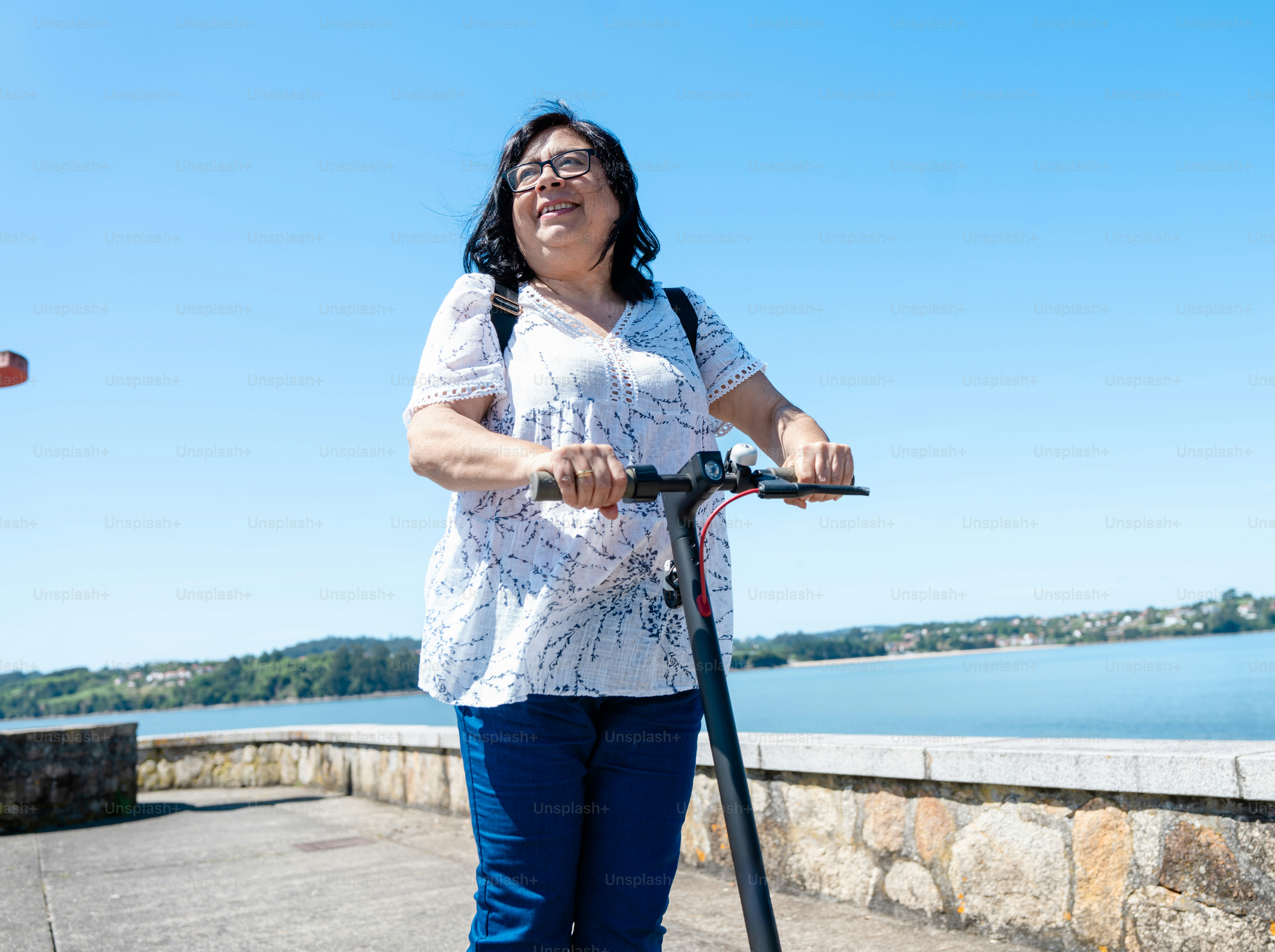 a woman riding a scooter near a body of water