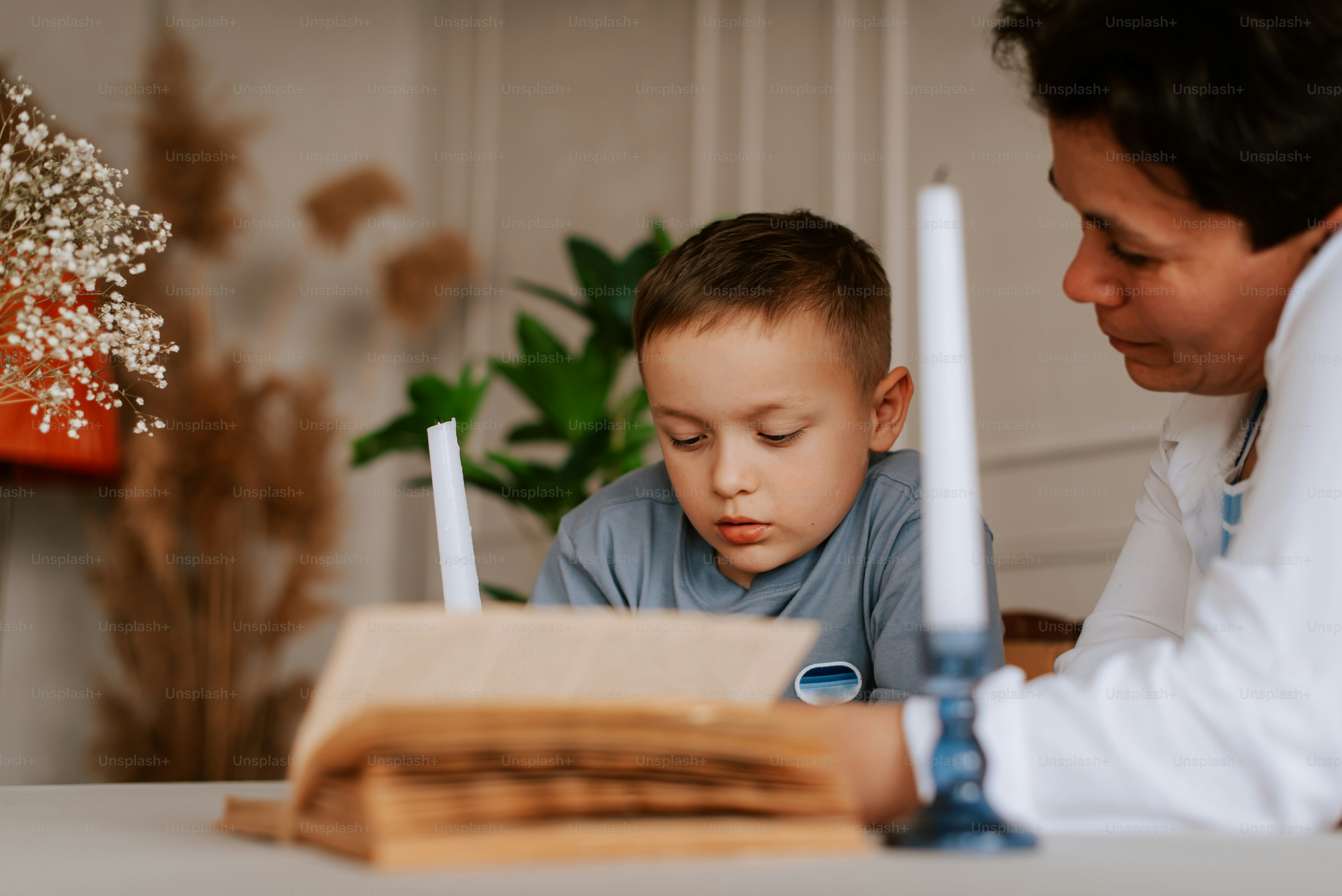 a little boy sitting at a table with a book