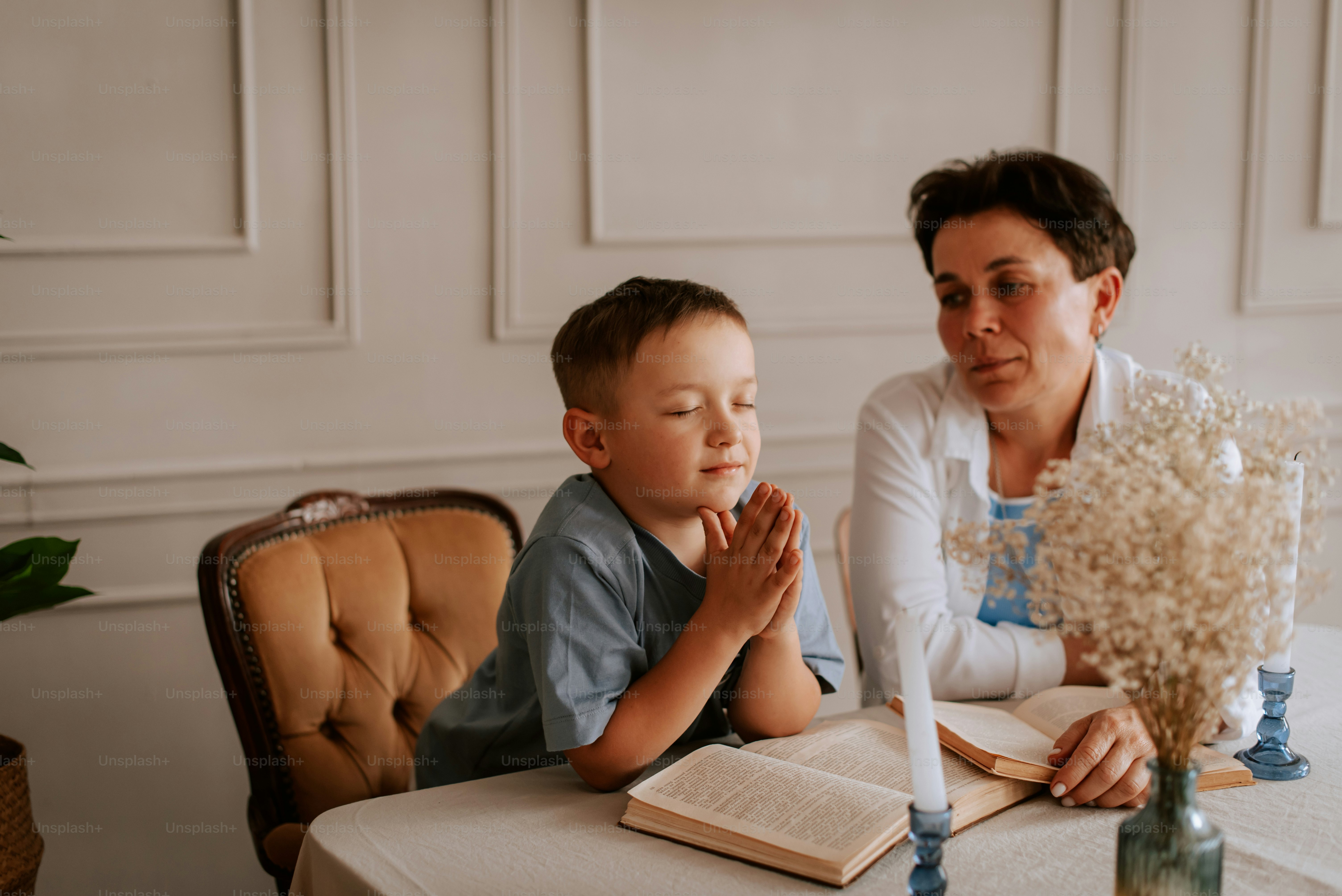 a woman and a boy sitting at a table with an open book