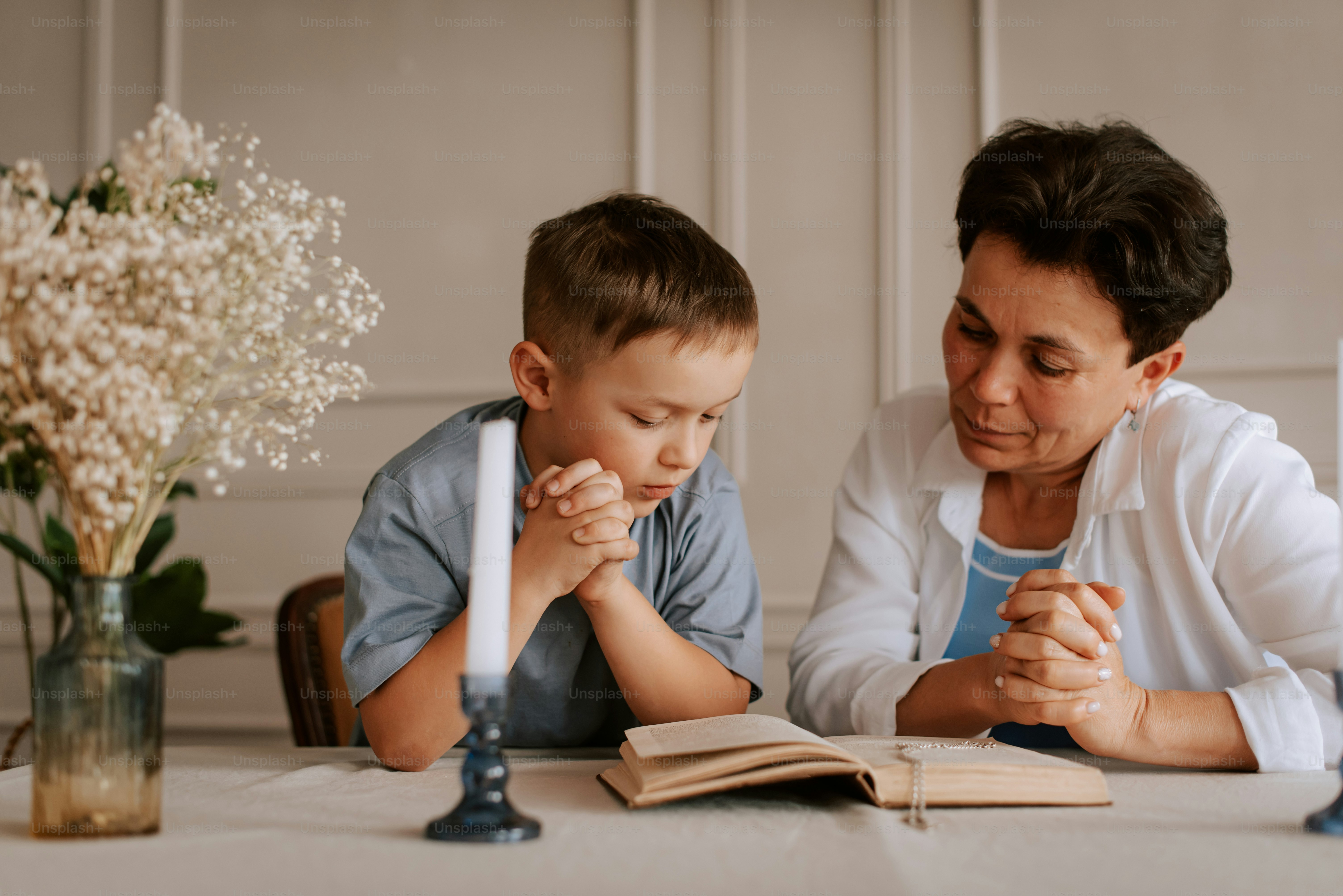 a woman and a boy sitting at a table with a book