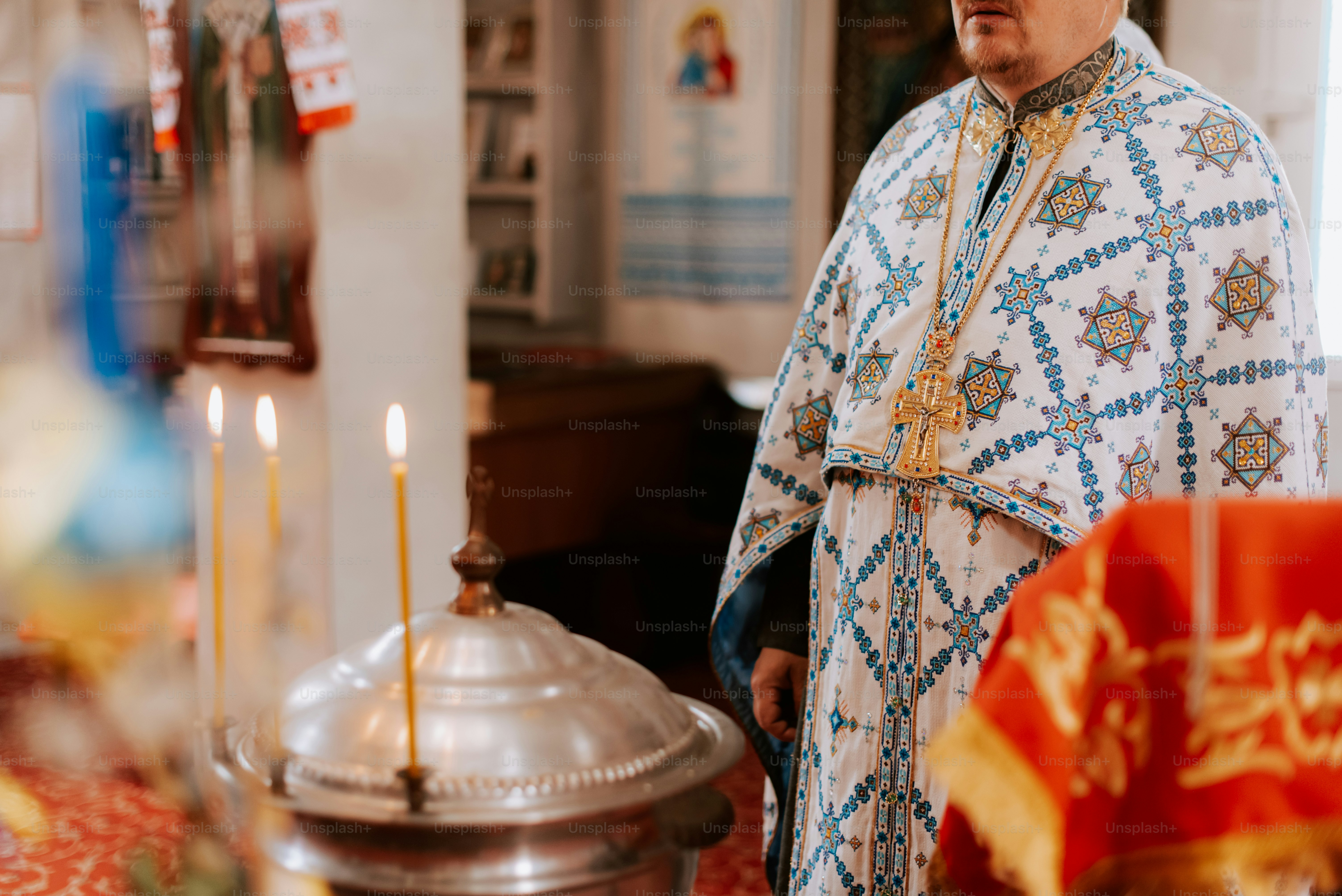 Ein Priester steht mit einer brennenden Kerze vor einer Kirchenbank