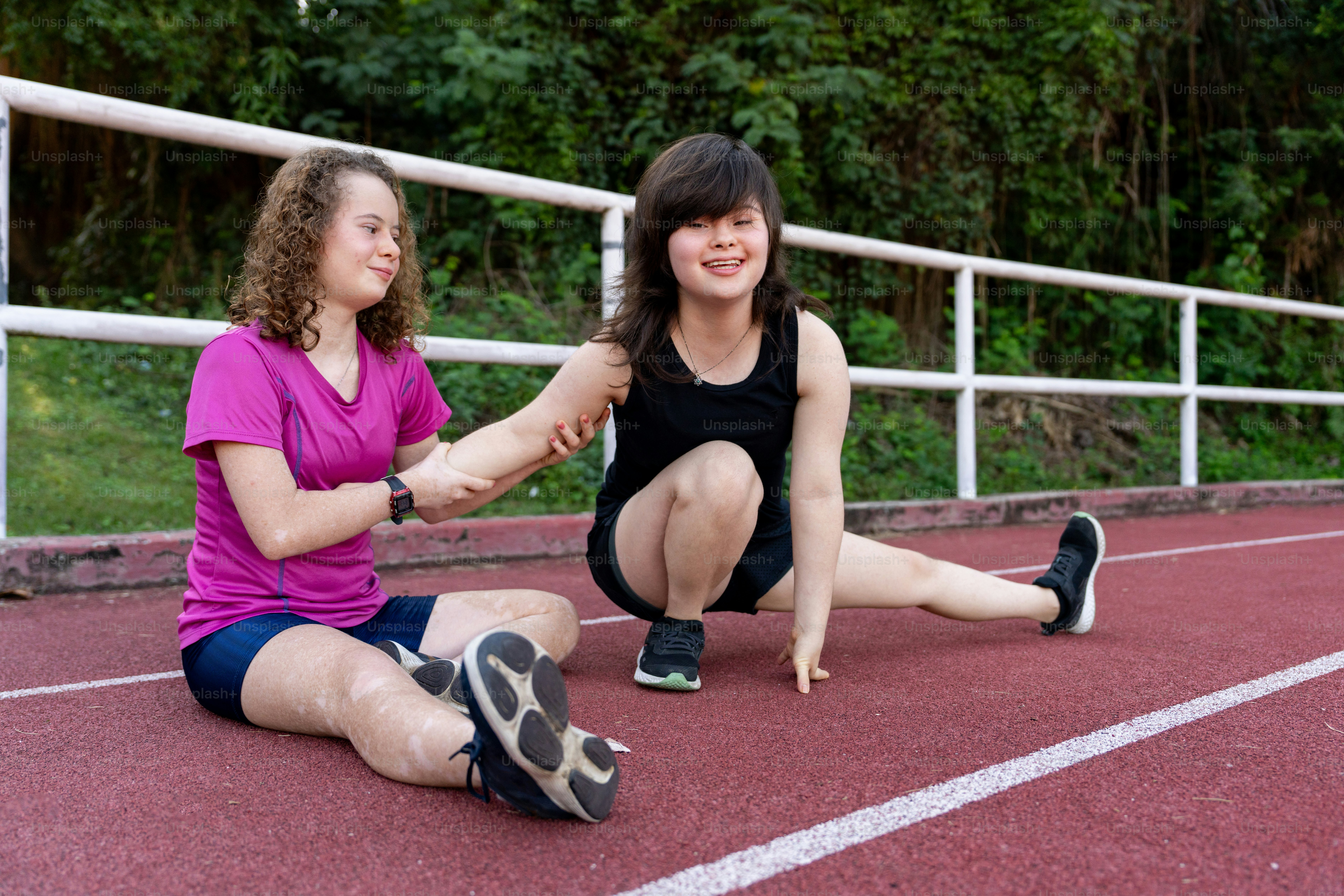 two young women sitting on a running track