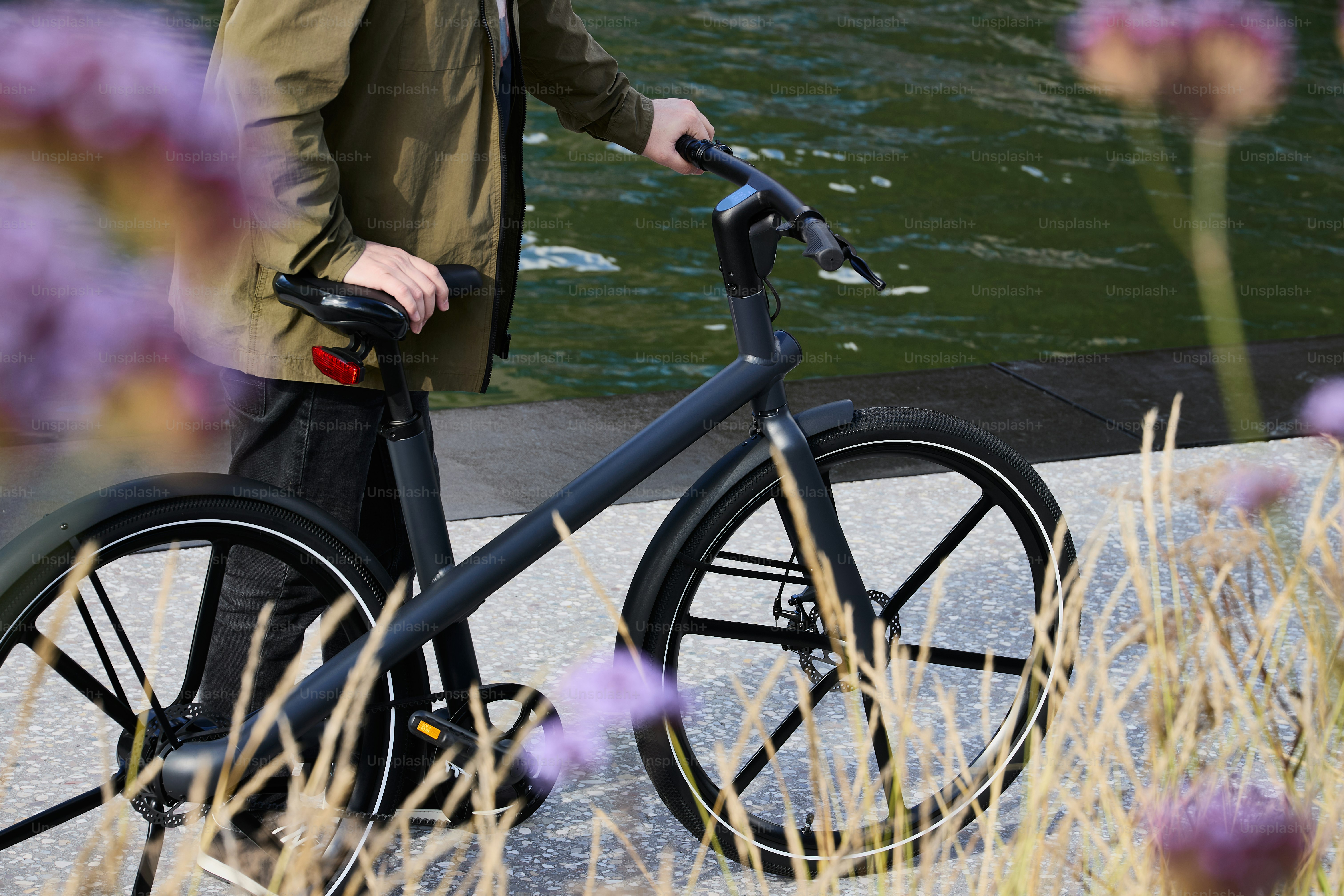 a man walking a bike next to a body of water