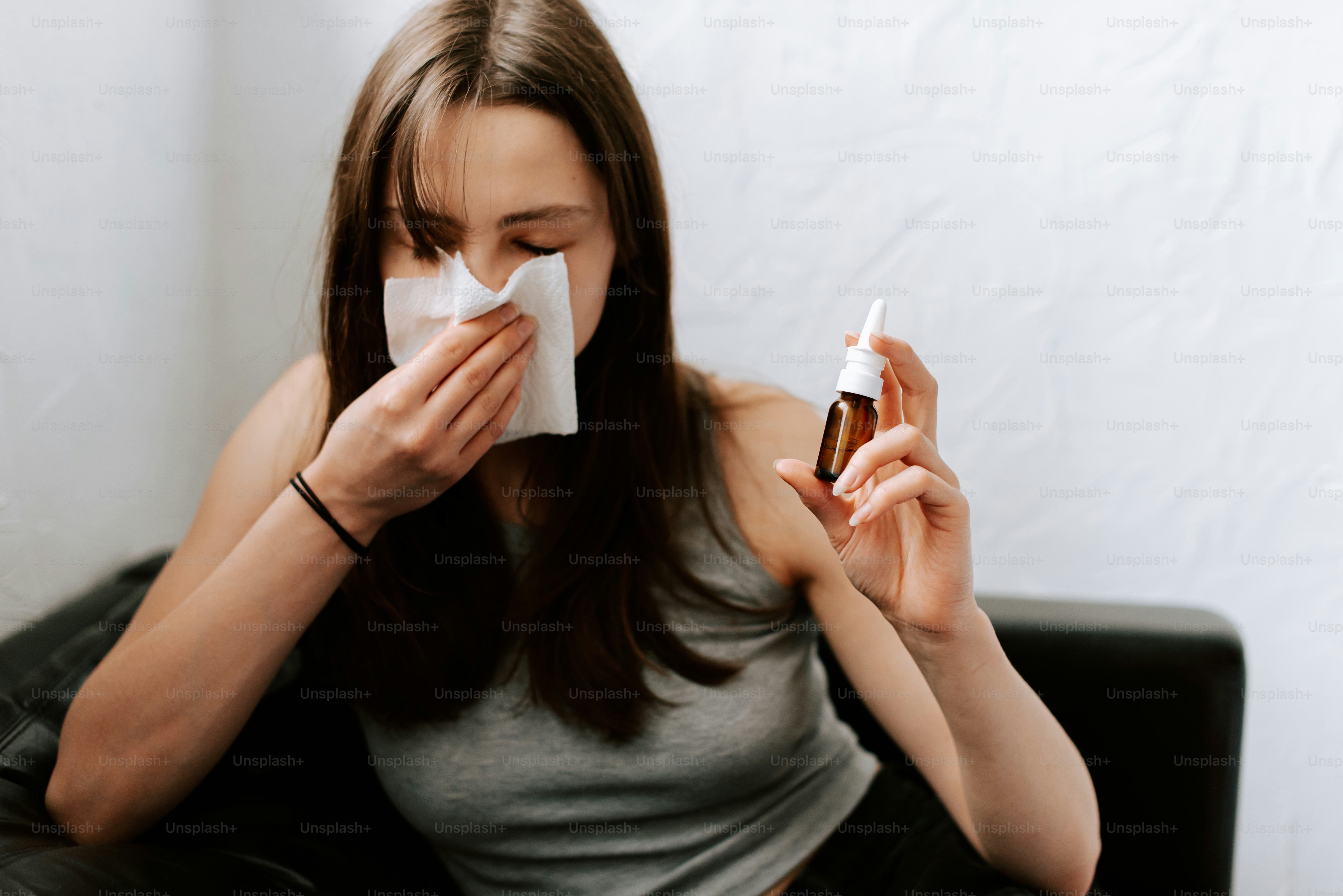 a woman sitting on a couch blowing her nose
