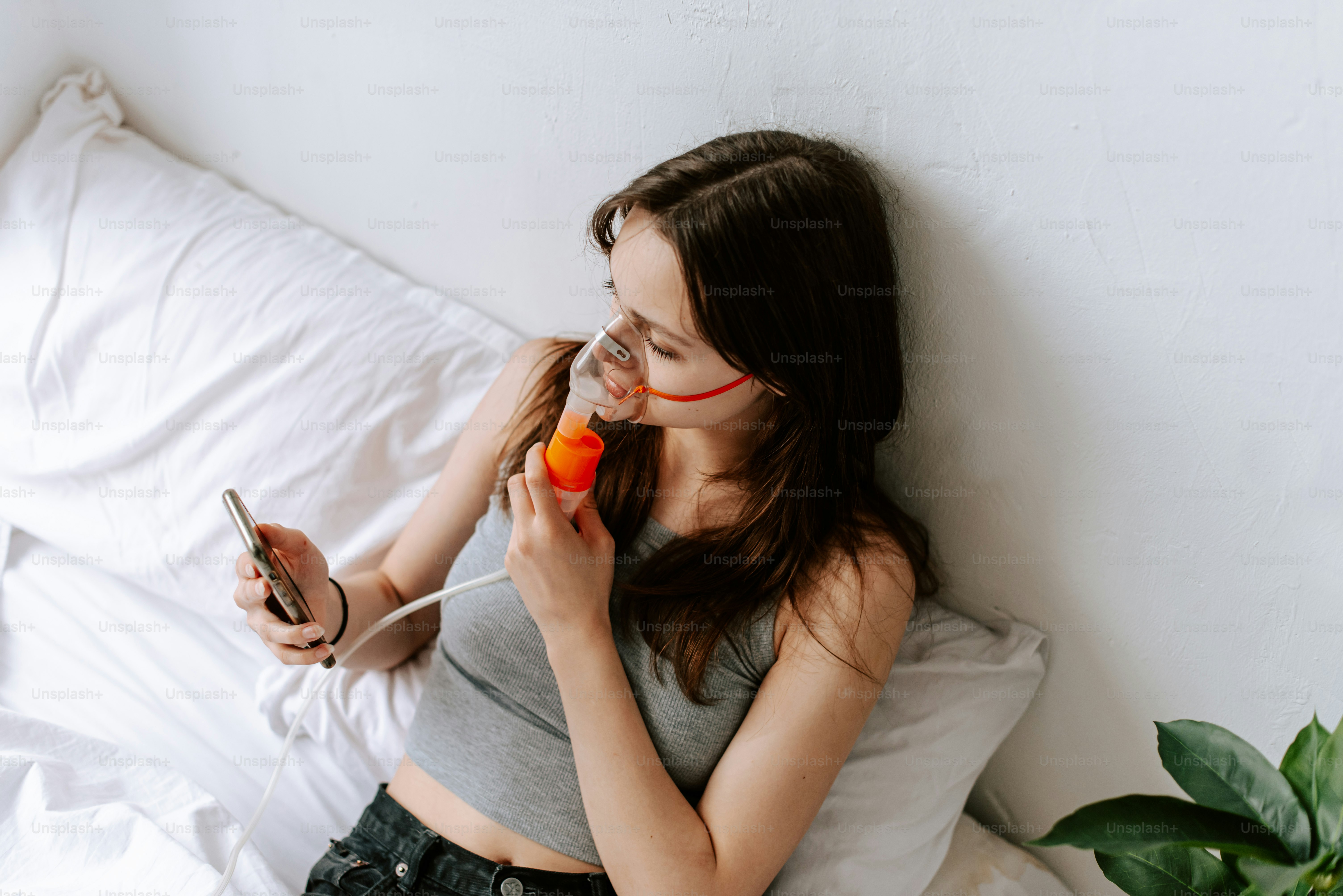 uma mulher deitada na cama com um telefone celular