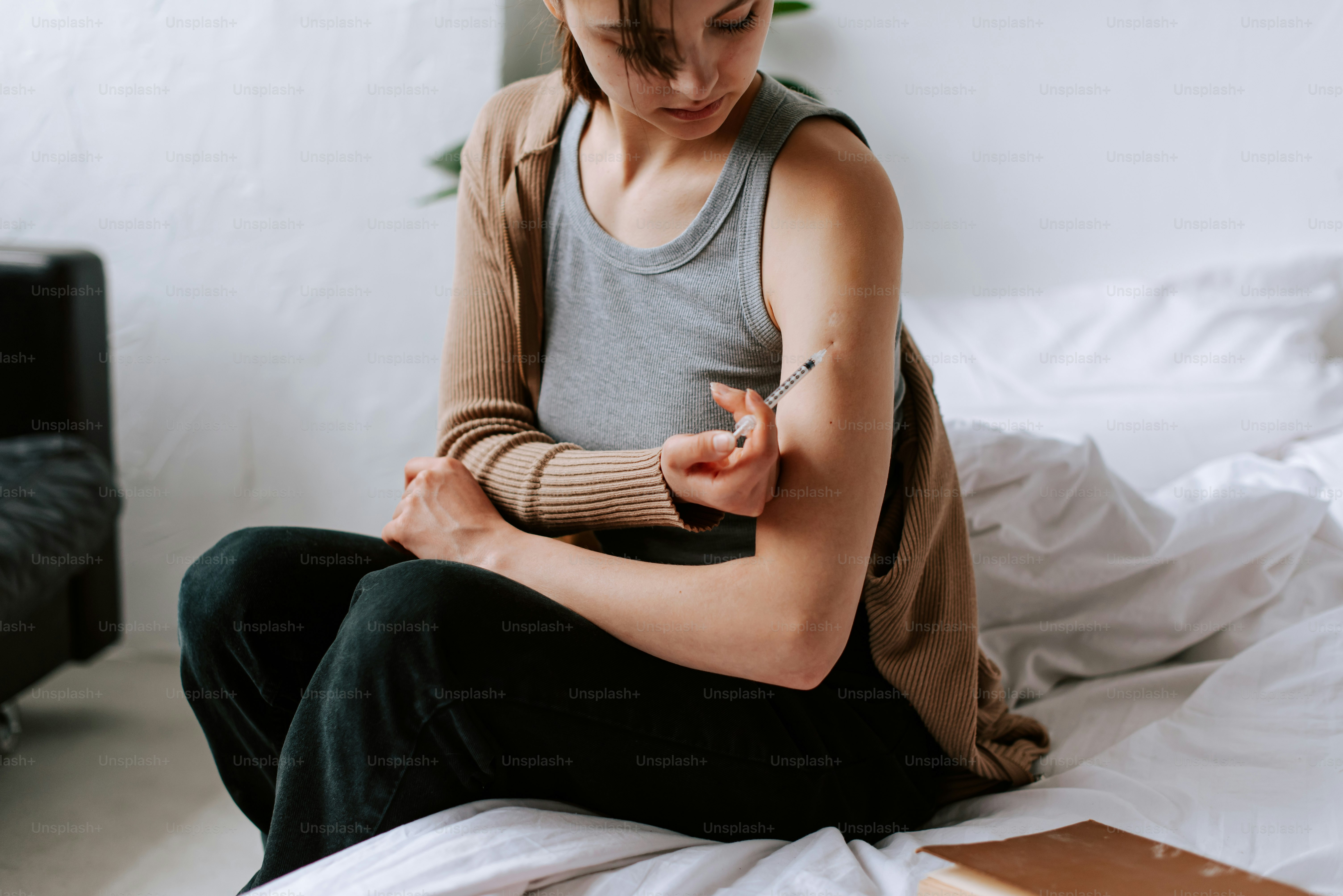 una persona seduta su un letto con un tatuaggio sul braccio