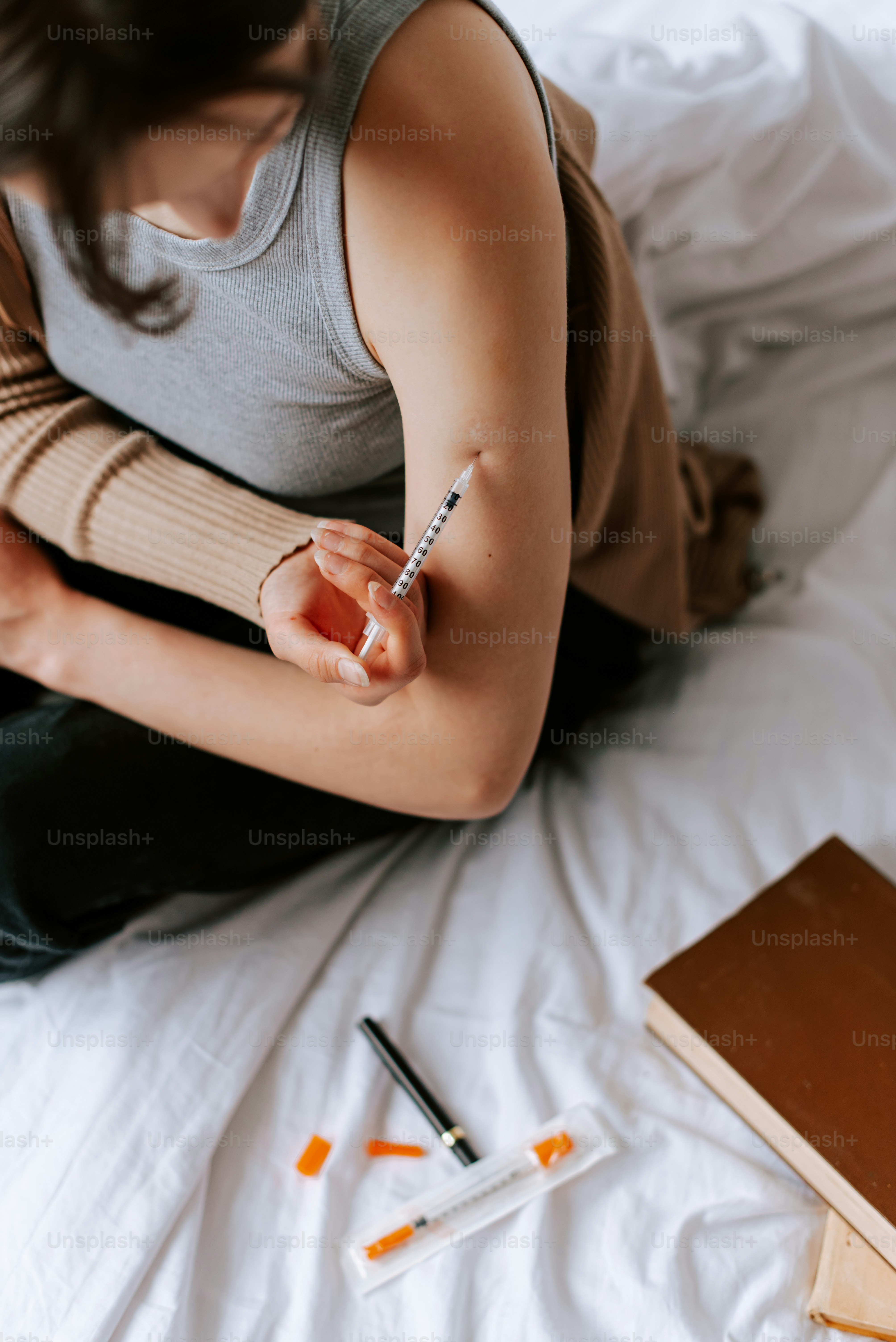 seorang wanita duduk di tempat tidur sambil memegang pena