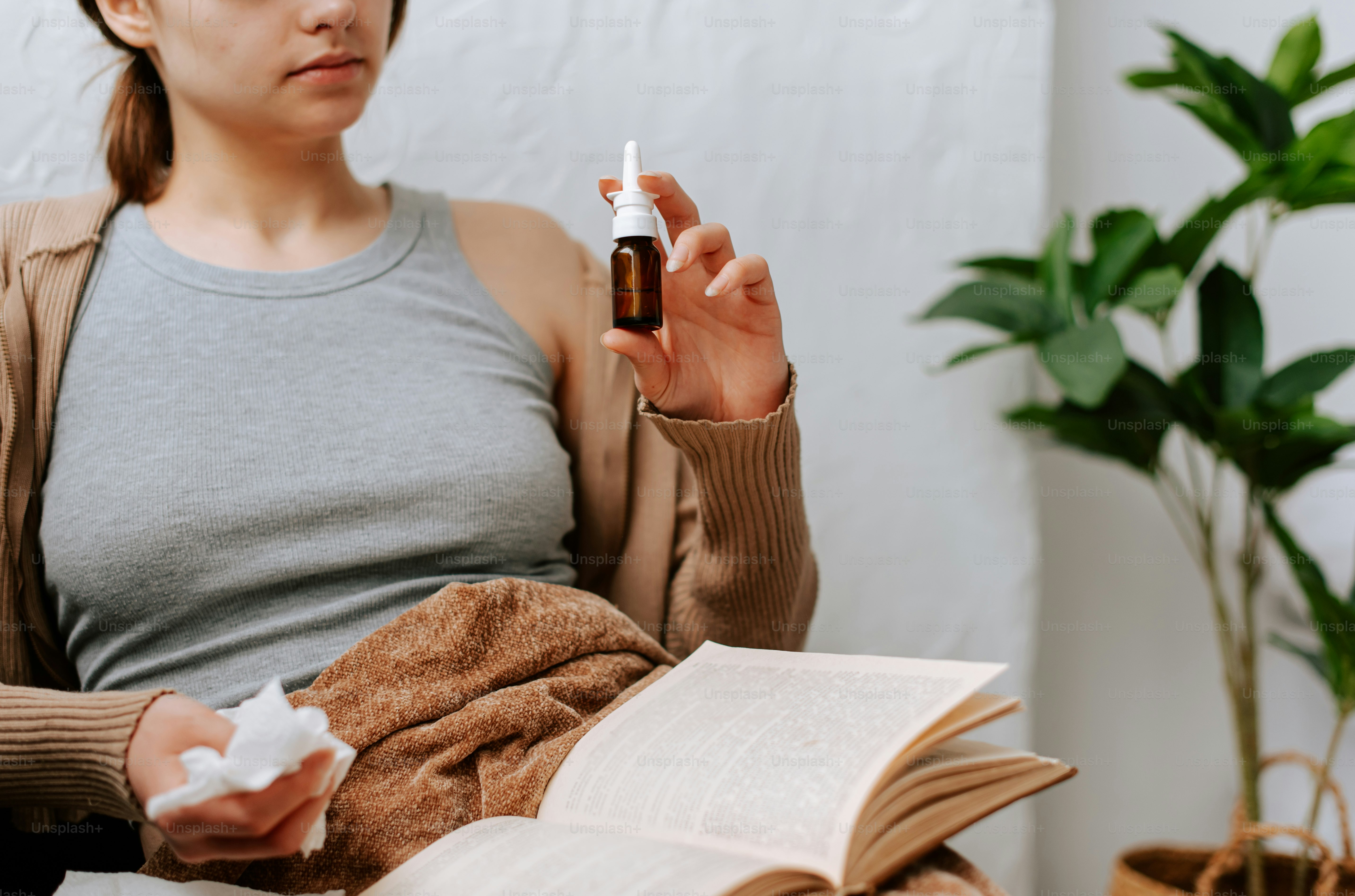 a woman sitting on a couch holding a bottle of medicine