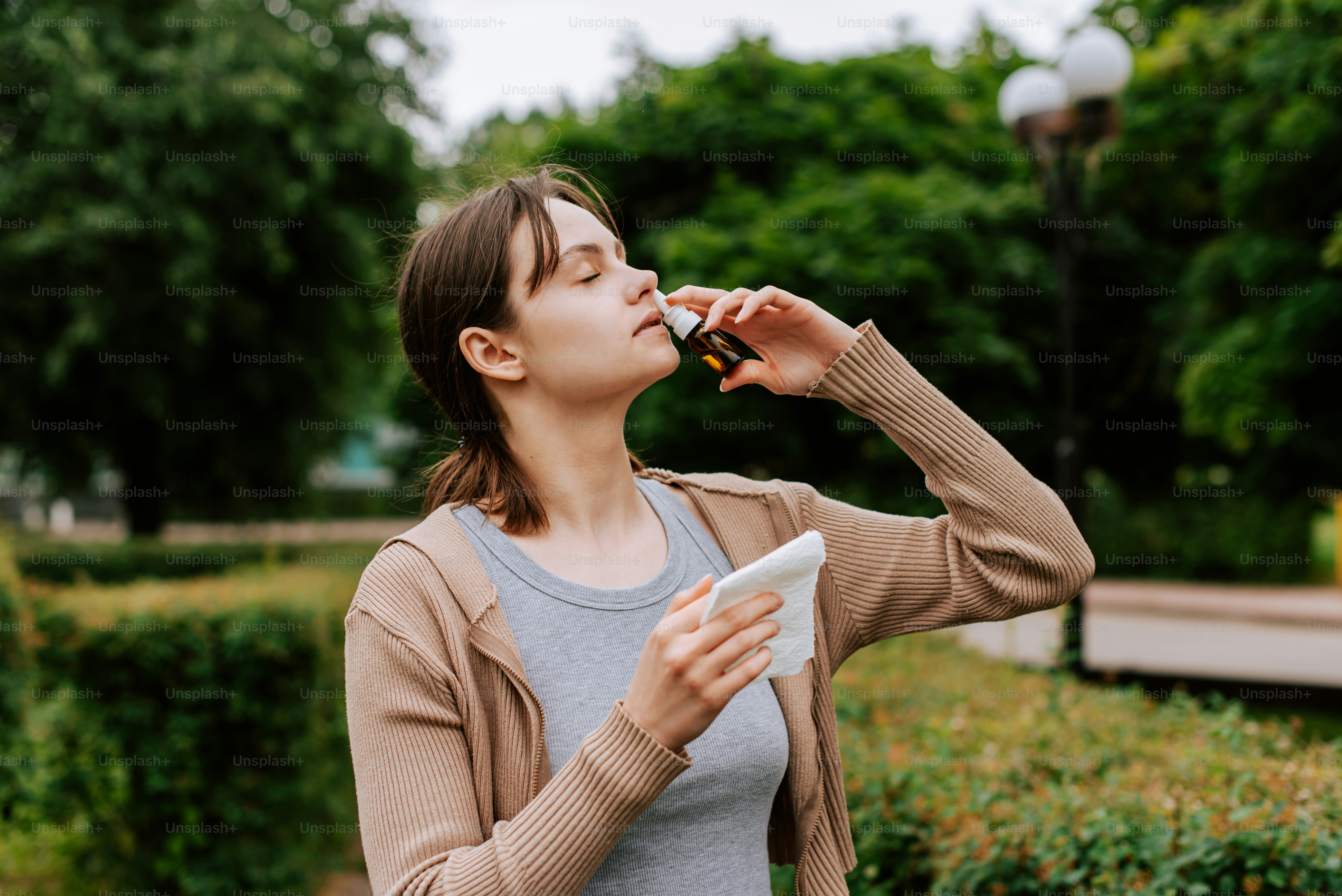 a woman eating something while standing in a park